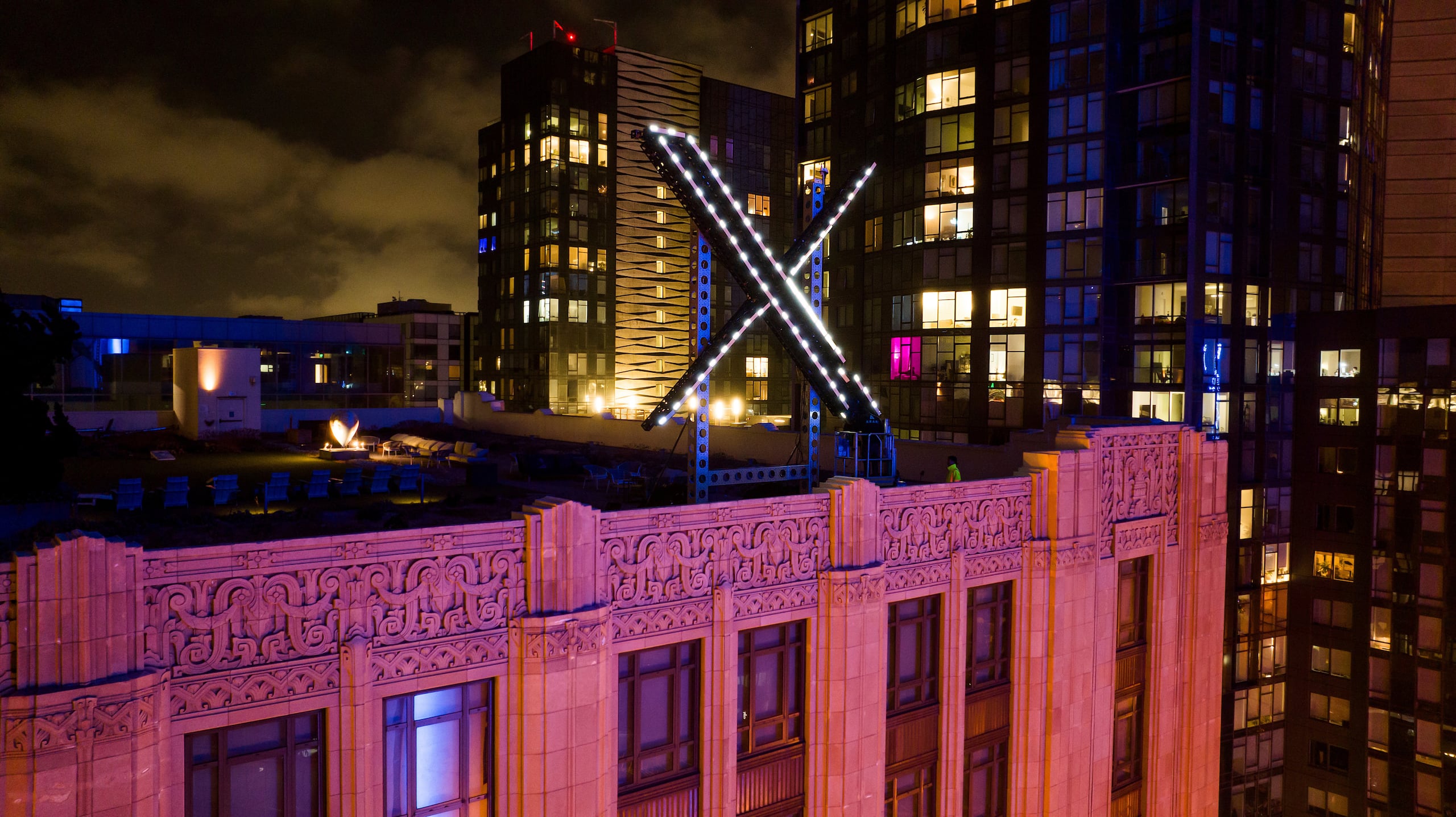 Trabajadores instalan iluminación en un letrero de X en la cima de la sede de la compañía, el 28 de julio de 2023, en San Francisco. (AP Foto/Noah Berger, Archivo)