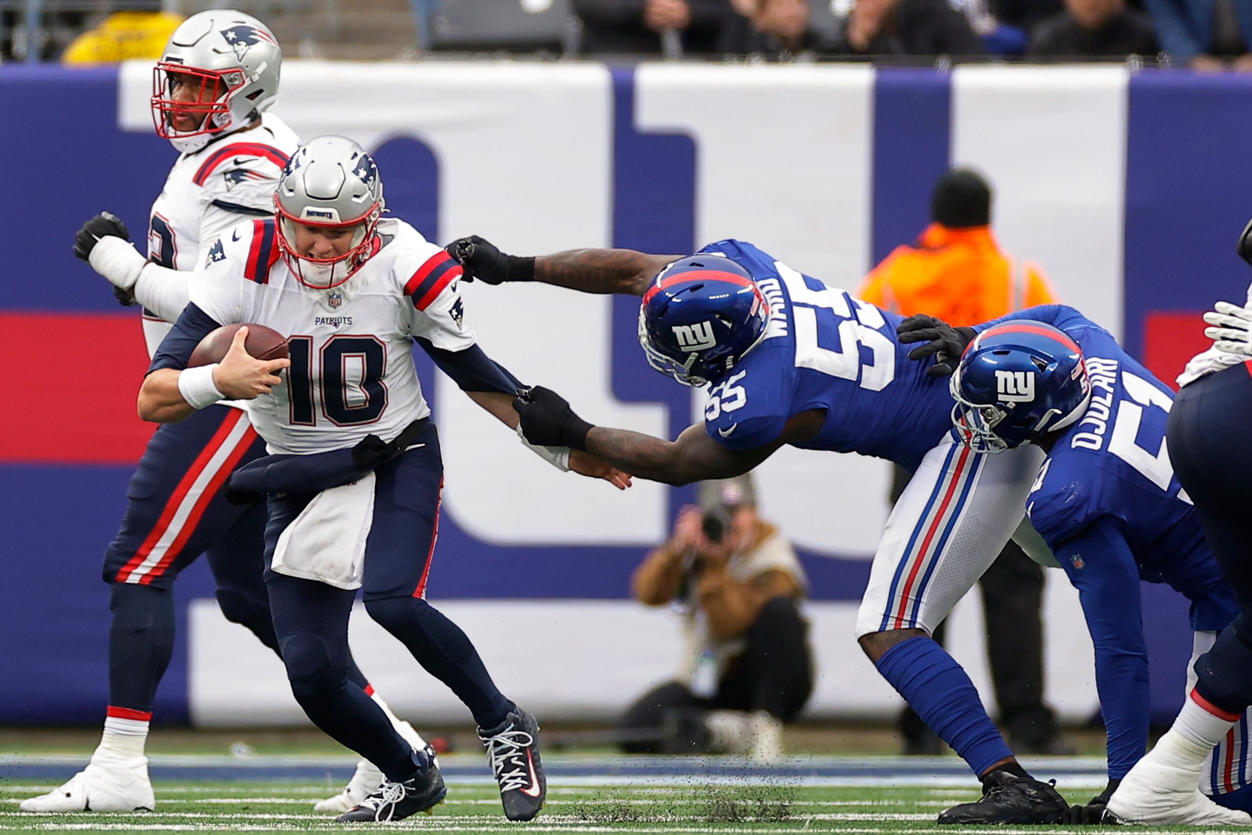 El linebacker de los Giants de Nueva York Jihad Ward (55) sujeta al quarterback de los Patrios de Nueva Inglaterra, Mac Jones (10), durante el partido entre Giants y Patriots en Nueva Jersey.