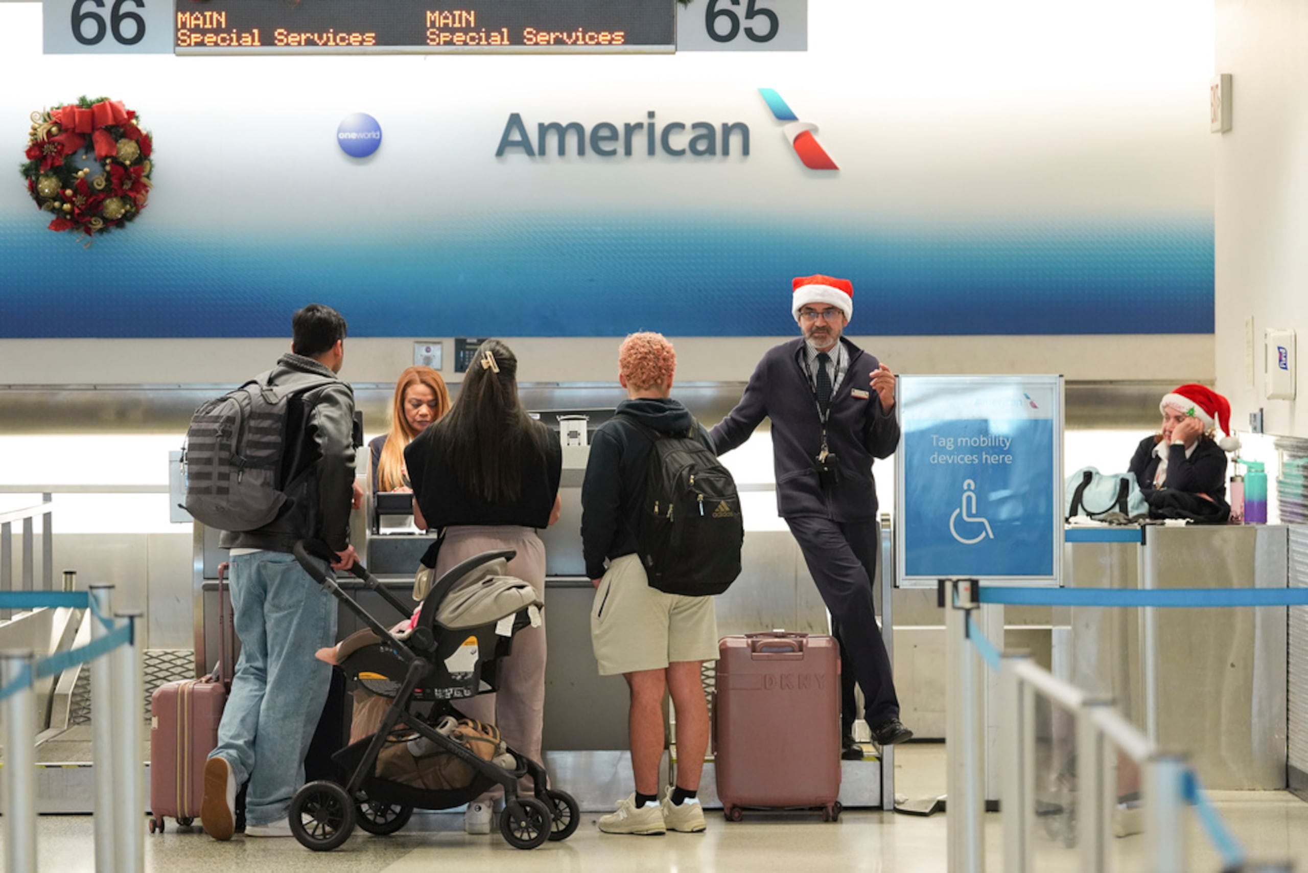 Empleados de American Airlines, algunos con gorros de Santa Claus, registran a los viajeros en la terminal de American en el Aeropuerto Internacional de Miami, en la víspera de Navidad, el 24 de diciembre de 2024, en Miami.