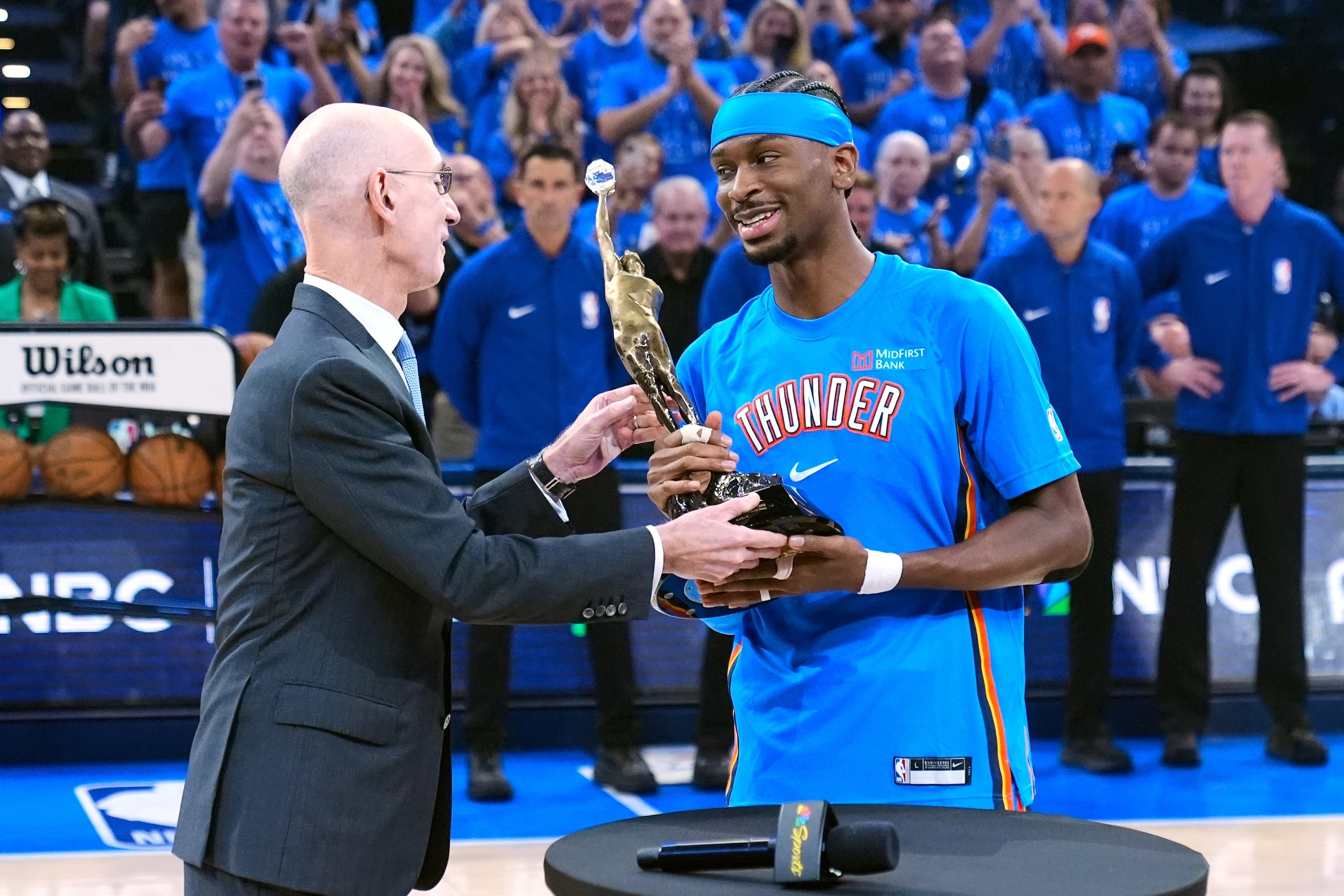 El comicionado de la NBA Adam Silver, izquierda, entrega a Shai Gilgeous-Alexander, del Thunder de Oklahoma City, el trofeo que lo acredita como el Jugador Más Valioso (MVP) de la NBA, previo al inicio del primer juego de las Finales de la Conferencia Oeste contra los Spurs de San Antonio, el lunes 18 de mayo de 2026, en Oklahoma City. (AP Foto/Tony Gutierrez)