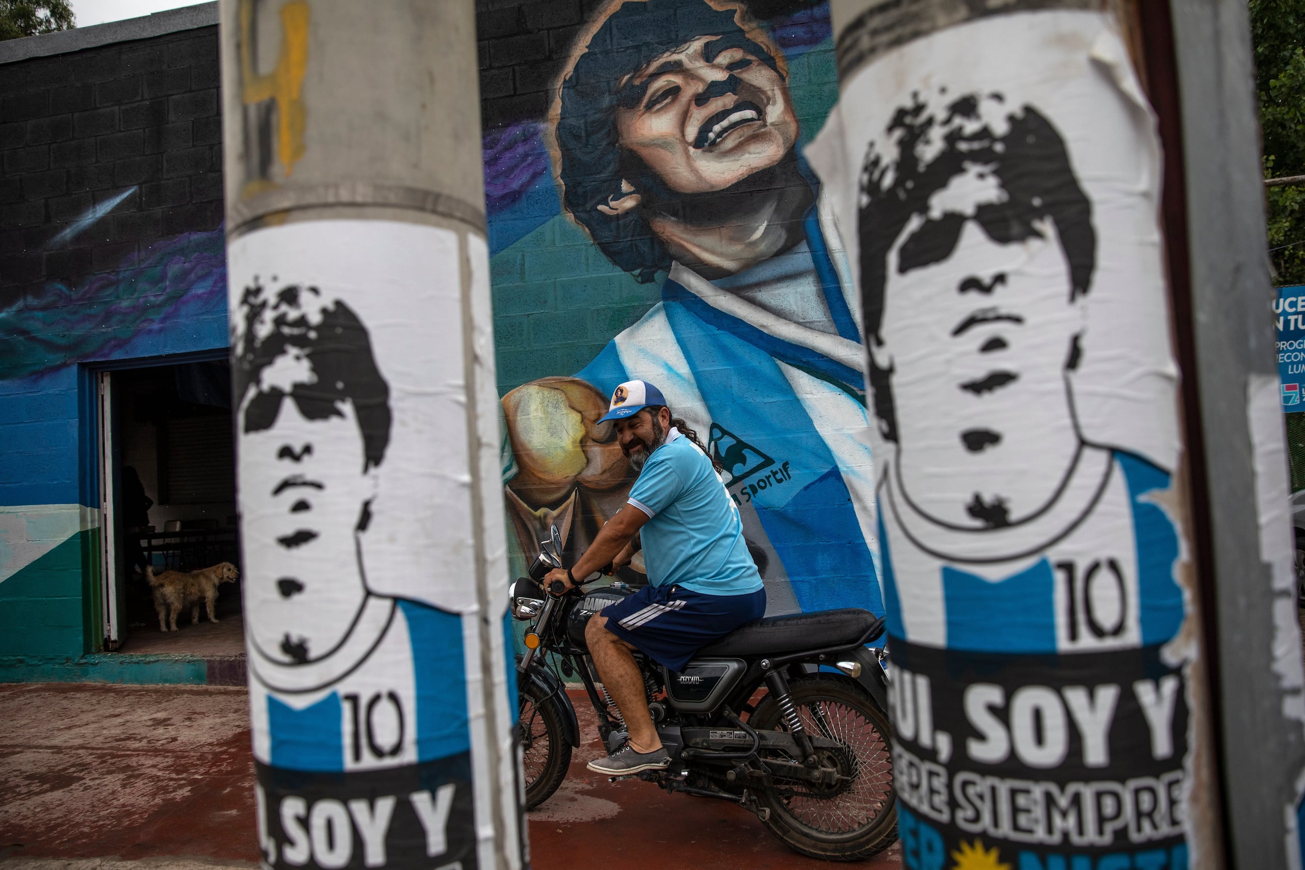 Un fan se apresta a arrancar su moto frente a un mural con la imagen de Diego Maradona, en el barrio de Fiorito, en Buenos Aires, el 25 de noviembre de 2021. (AP Foto/Rodrigo Abd)