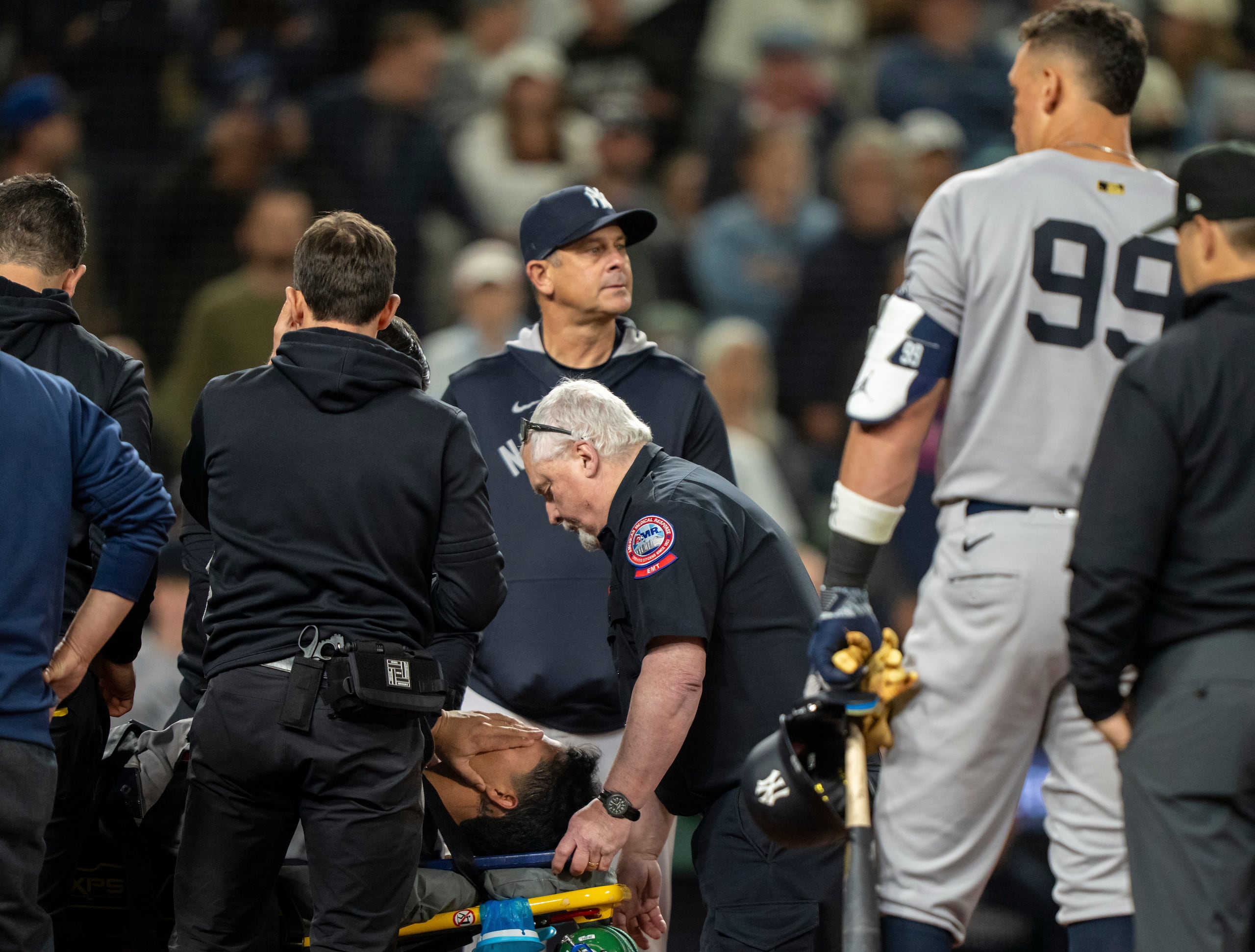 Oswaldo Cabrera de los Yankees de Nueva York se cubre el rostro al ser sacado en camilla tras sufrir una lesión en el noveno inning del juego contra los Marineros de Seattle, el lunes 12 de mayo de 2025, en Seattle.