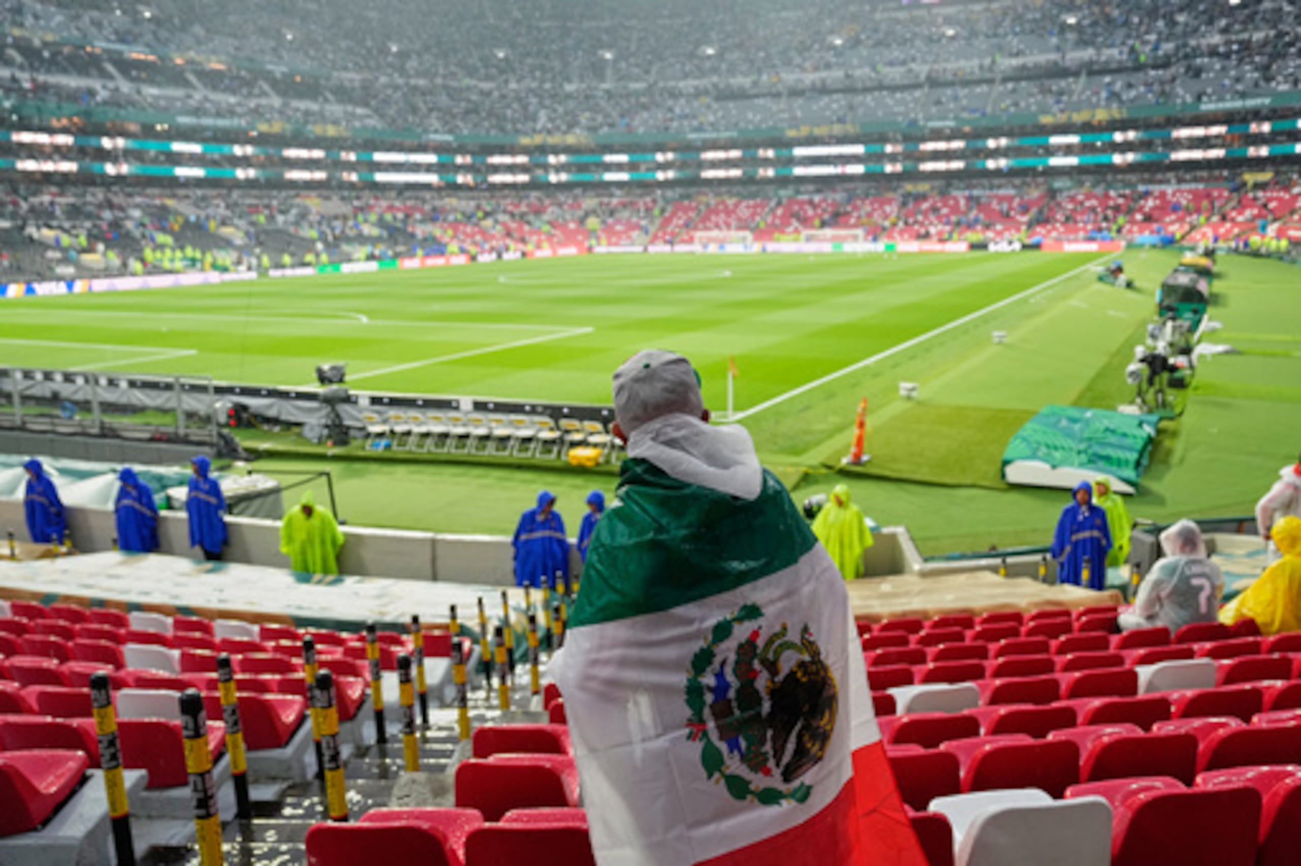 Un aficionado mexicano espera bajo la lluvia en el Estadio Azteca.