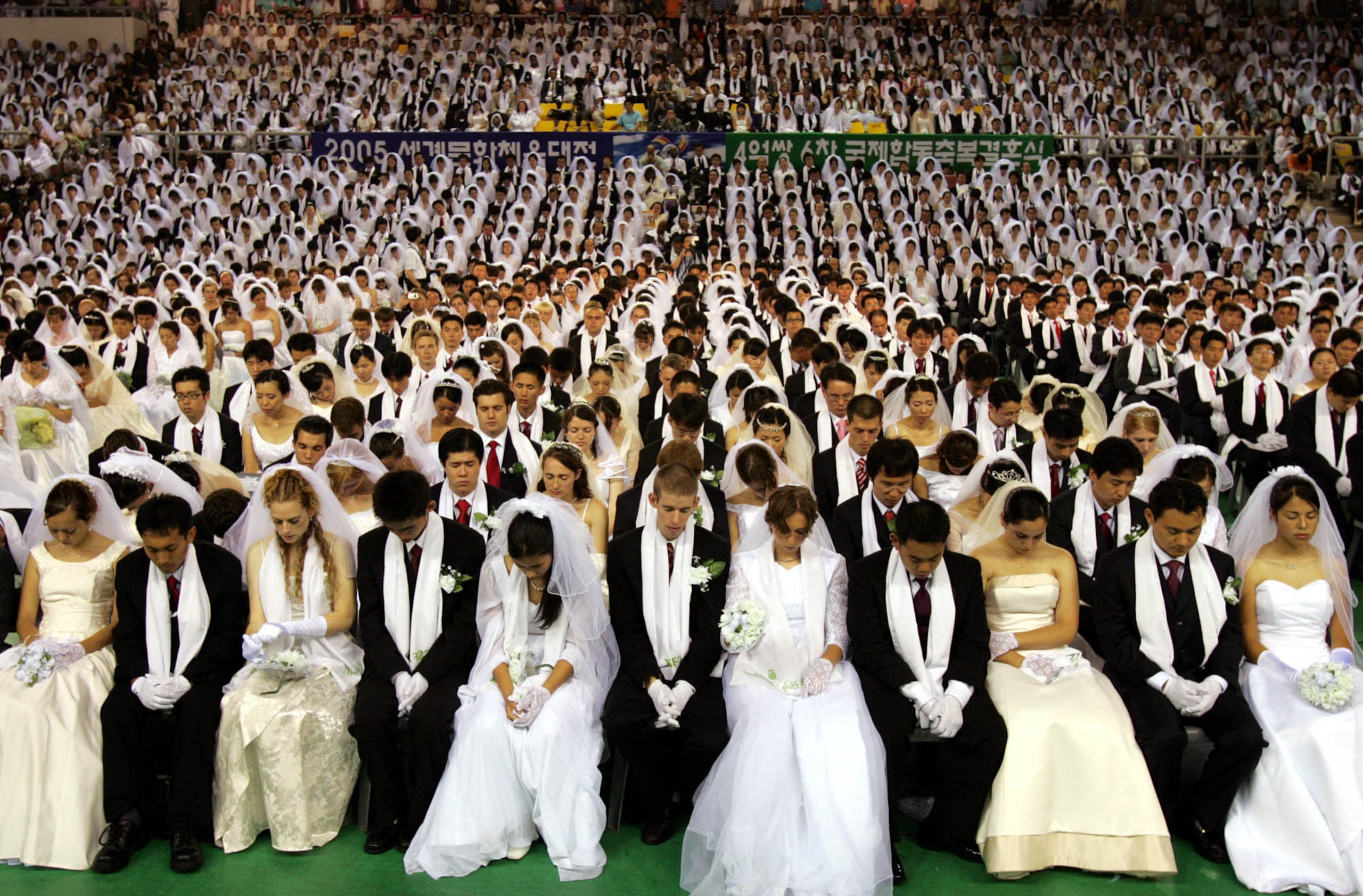Unas 4,600 parejas, algunas provenientes de países extranjeros, rezan durante la ceremonia de bodas masivas organizada por la Iglesia de la Unificación del reverendo Sun Myung Moon en Cheonan, Corea del Sur, el 1 de agosto de 2005. En total, se esperaba que 400 millones de parejas se casaran en 545 sedes en más de 180 países.