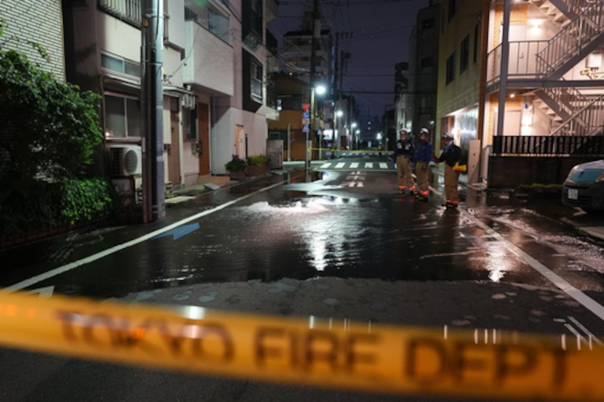 Los equipos de primera intervención del Cuerpo de Bomberos de Tokio se encuentran en una calle parcialmente inundada en la madrugada del domingo 23 de agosto de 2026, tras la rotura de una tubería de agua a raíz de un terremoto que sacudió la zona y las prefecturas vecinas. (Kazuki Kozaki/Kyodo News vía AP)