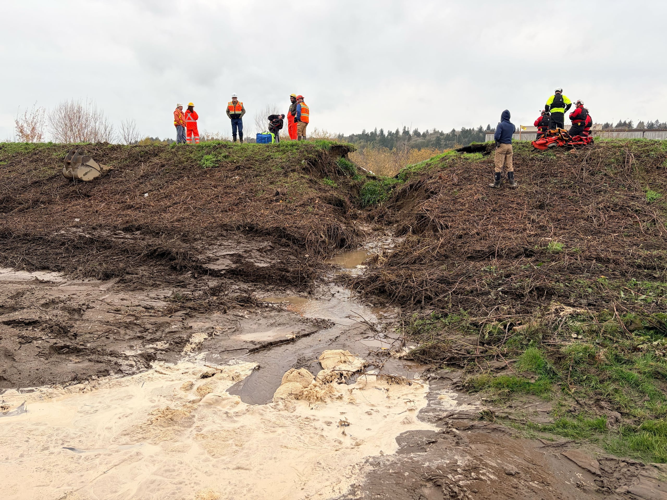 Workers gather at the site of the breached Desimone Levee in Tukwila, Wash., Monday, Dec. 15, 2025. (Ellen Banner/The Seattle Times via AP)