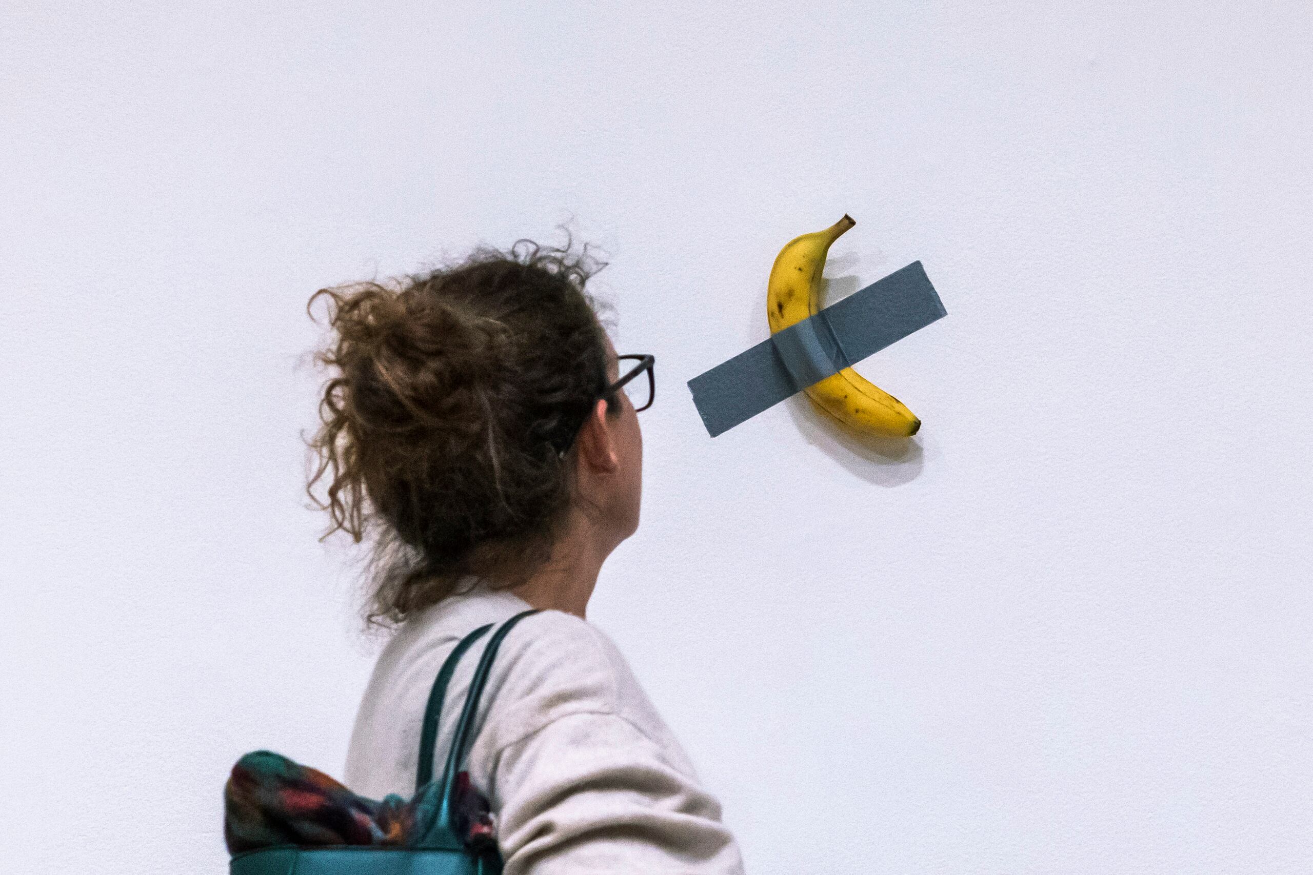 Una mujer mira la obra del artista Maurizio Cattelan.