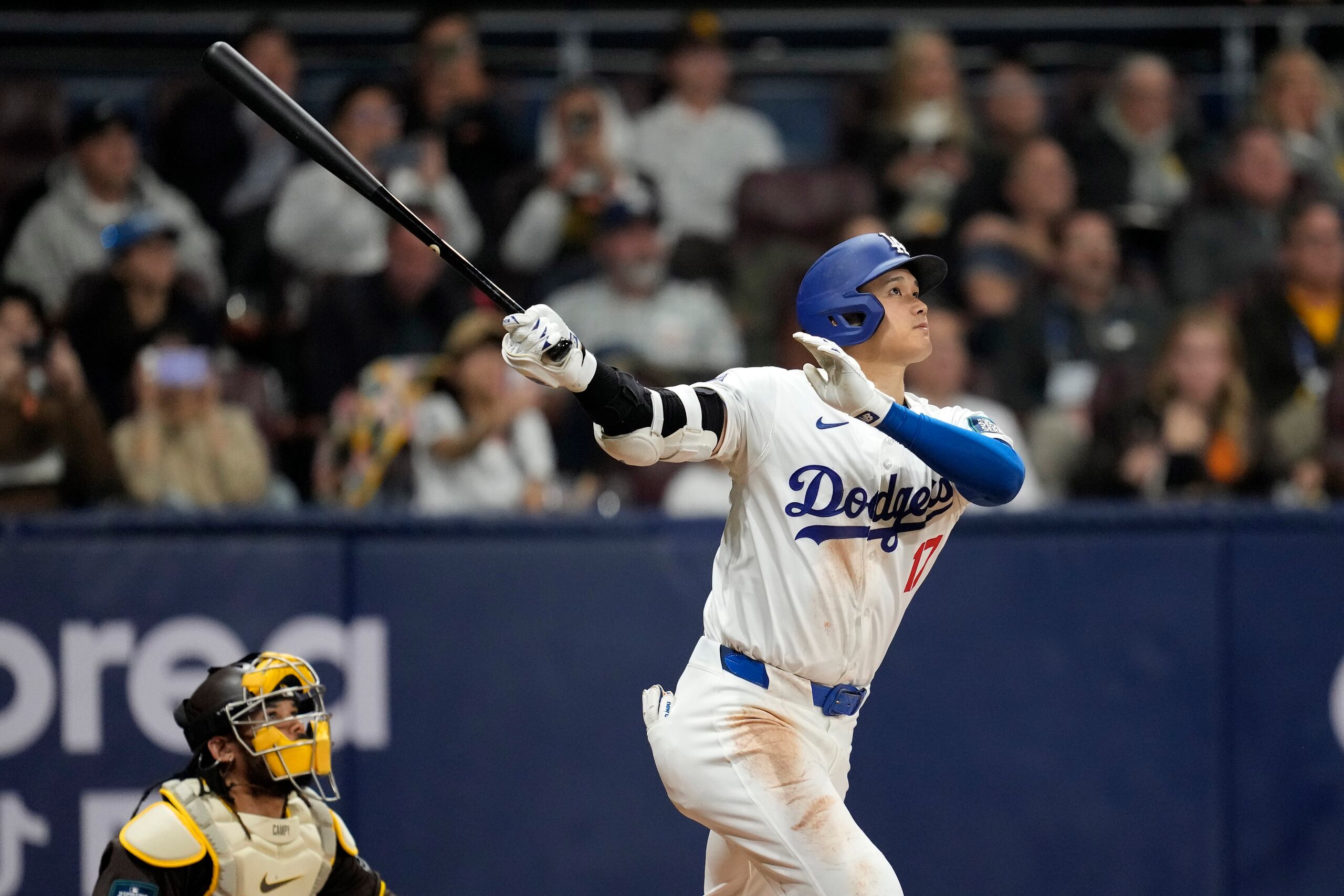 El bateador designado de los Dodgers de Los Ángeles, Shohei Ohtani, batea un elevado de sacrificio mientras lo observa el cátcher de los Padres de San Diego, Luis Campusano.