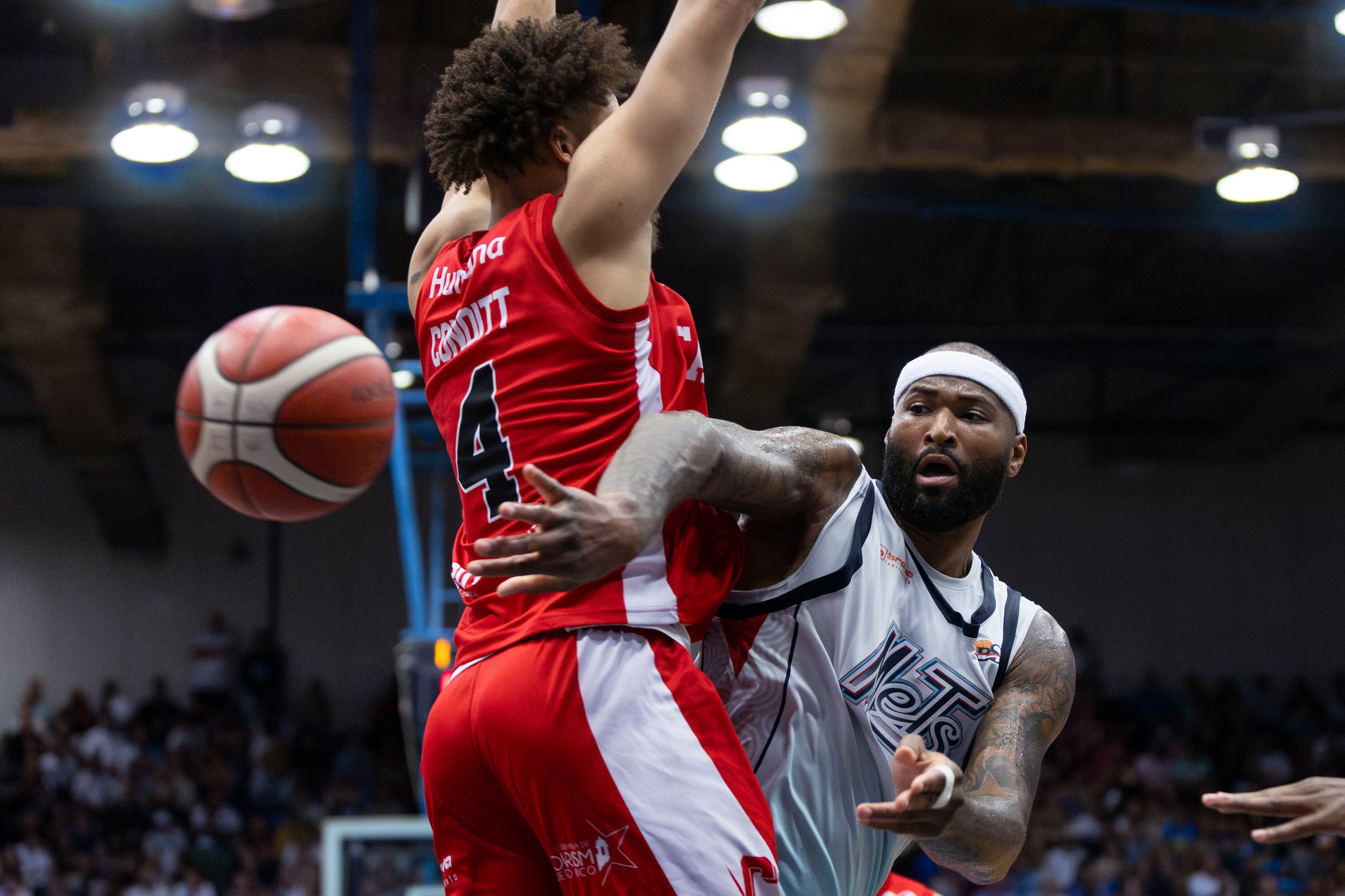 DeMarcus Cousins pasa el balón ante la defensa de George Conditt IV en las semifinales del BSN entre los Mets de Guaynabo y los Gigantes de Carolina en 2023.