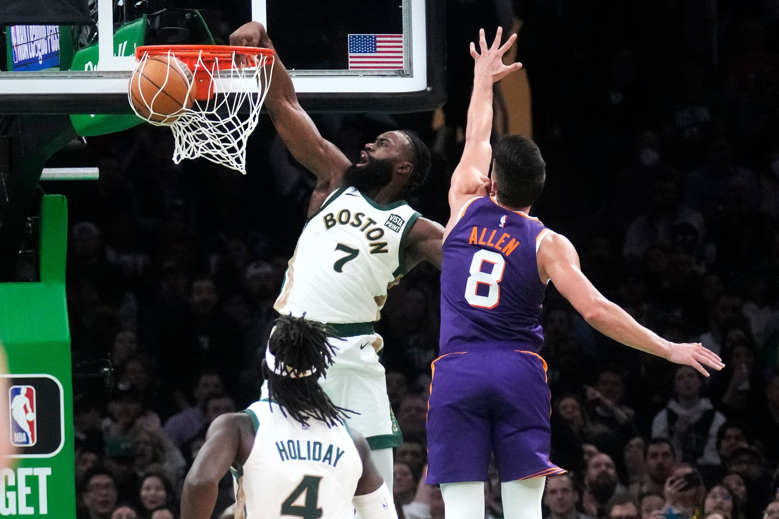 El escolta de los Celtics de Boston, Jaylen Brown, donquea después de superar al escolta de los Suns de Phoenix, Grayson Allen.