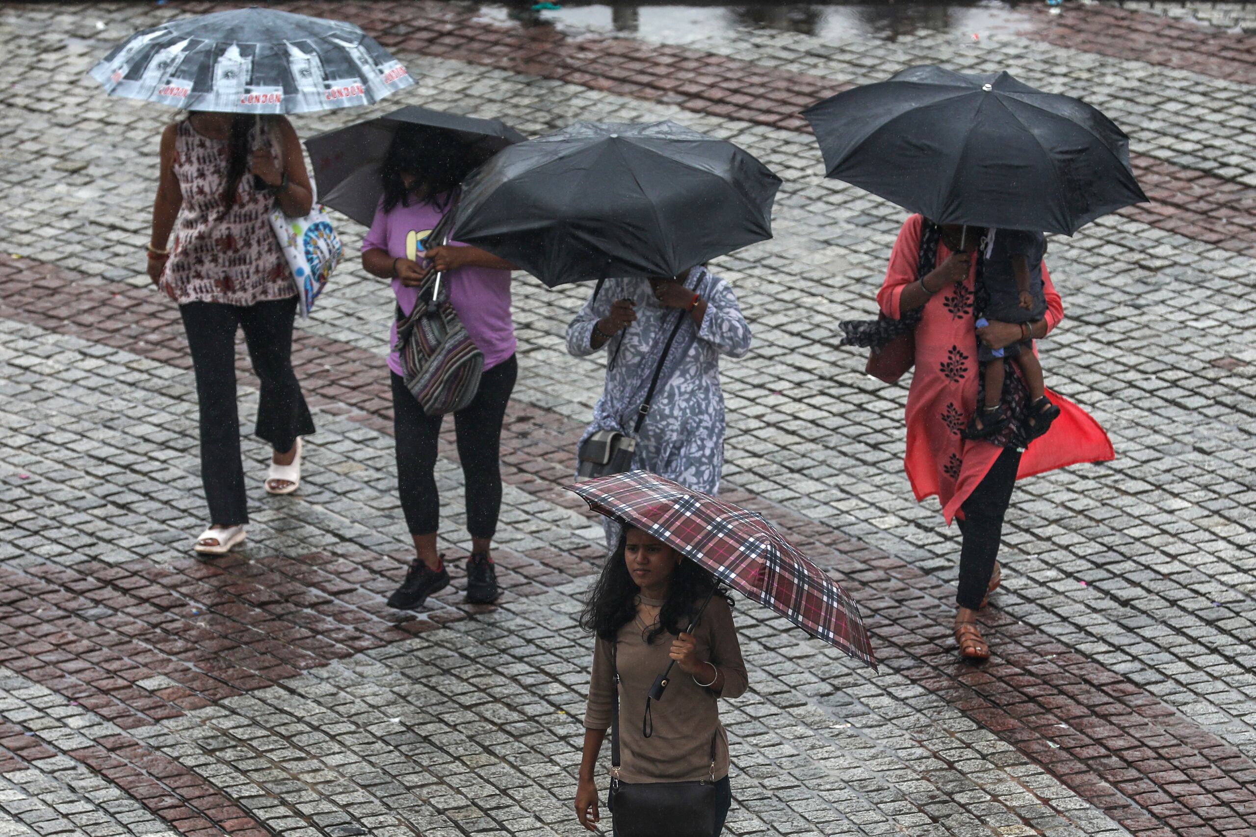 Varias personas se protegen de lluvia en Bombay, una de las ciudades de la India para las que se ha emitido una alerta por fuertes precipitaciones. EFE/EPA/DIVYAKANT SOLANKI