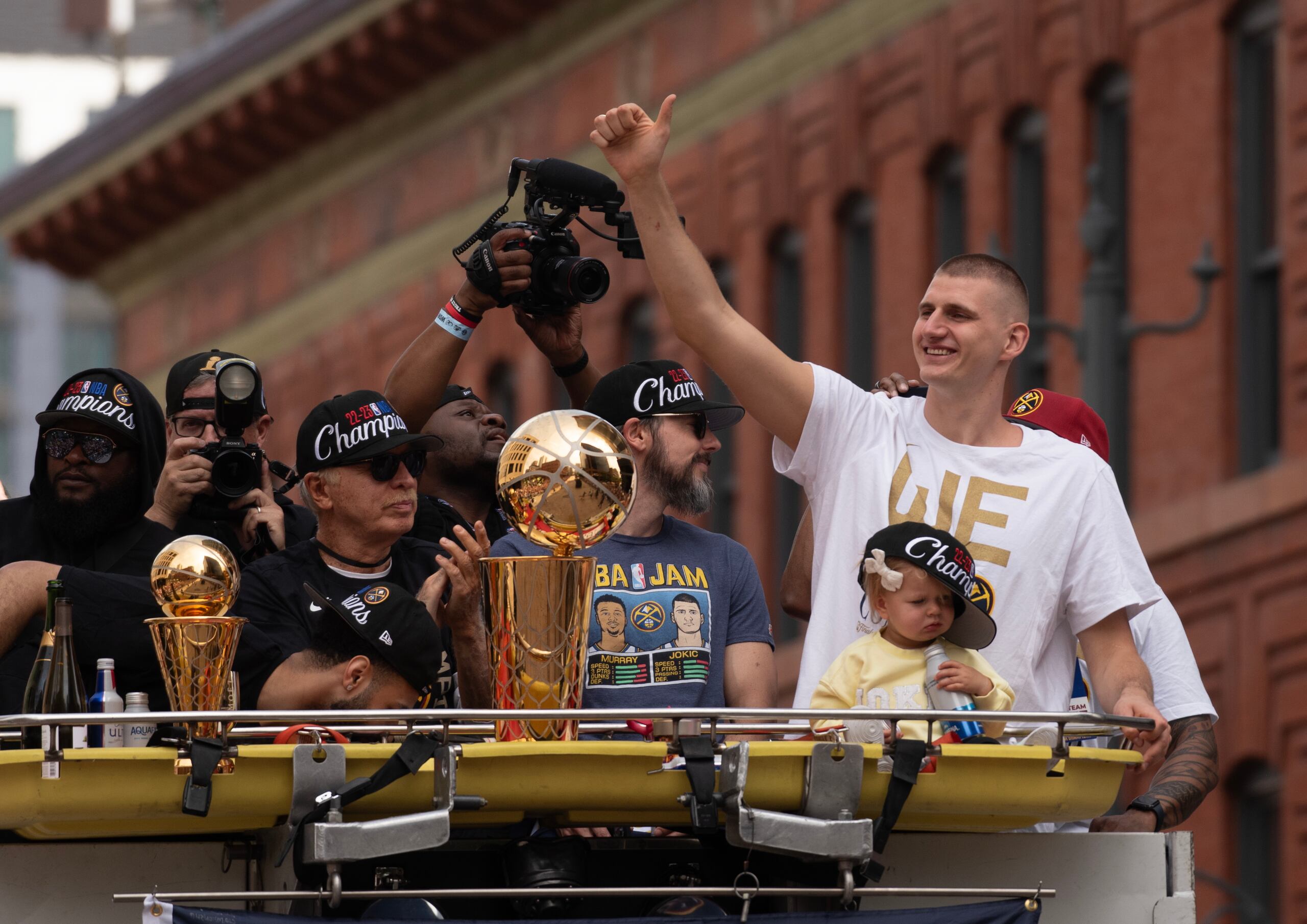 El pívot de los Denver Nuggets, Nikola Jokic, a la derecha, encabeza el acto de celebración del título de la NBA. Frente a él su pequeña hija.