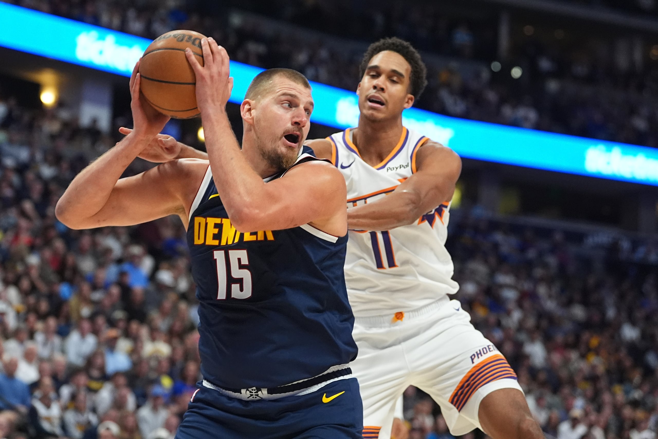 Nikola Jokic, pívot de los Nuggets de Denver, a la izquierda, captura un rebote mientras Oso Ighodaro, delantero de los Suns de Phoenix, a la derecha.