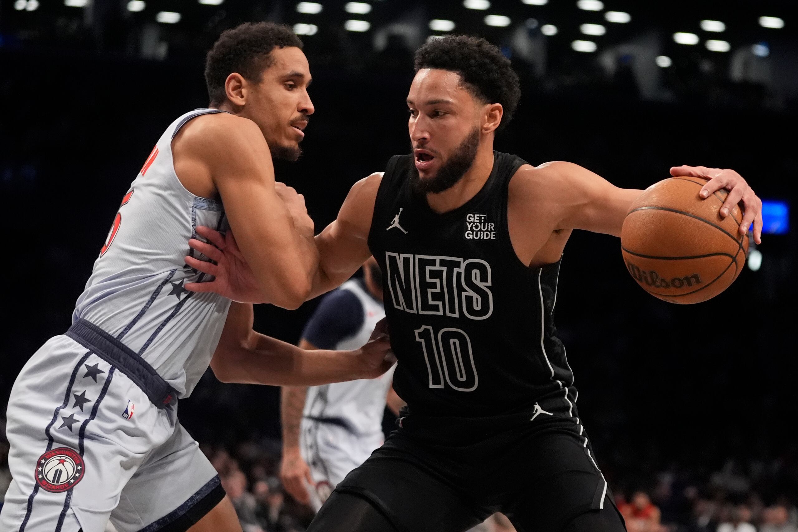 Ben Simmons, de los Nets de Brooklyn, trata de avanzar frente a Malcolm Brogdon, de los Wizards de Washington.