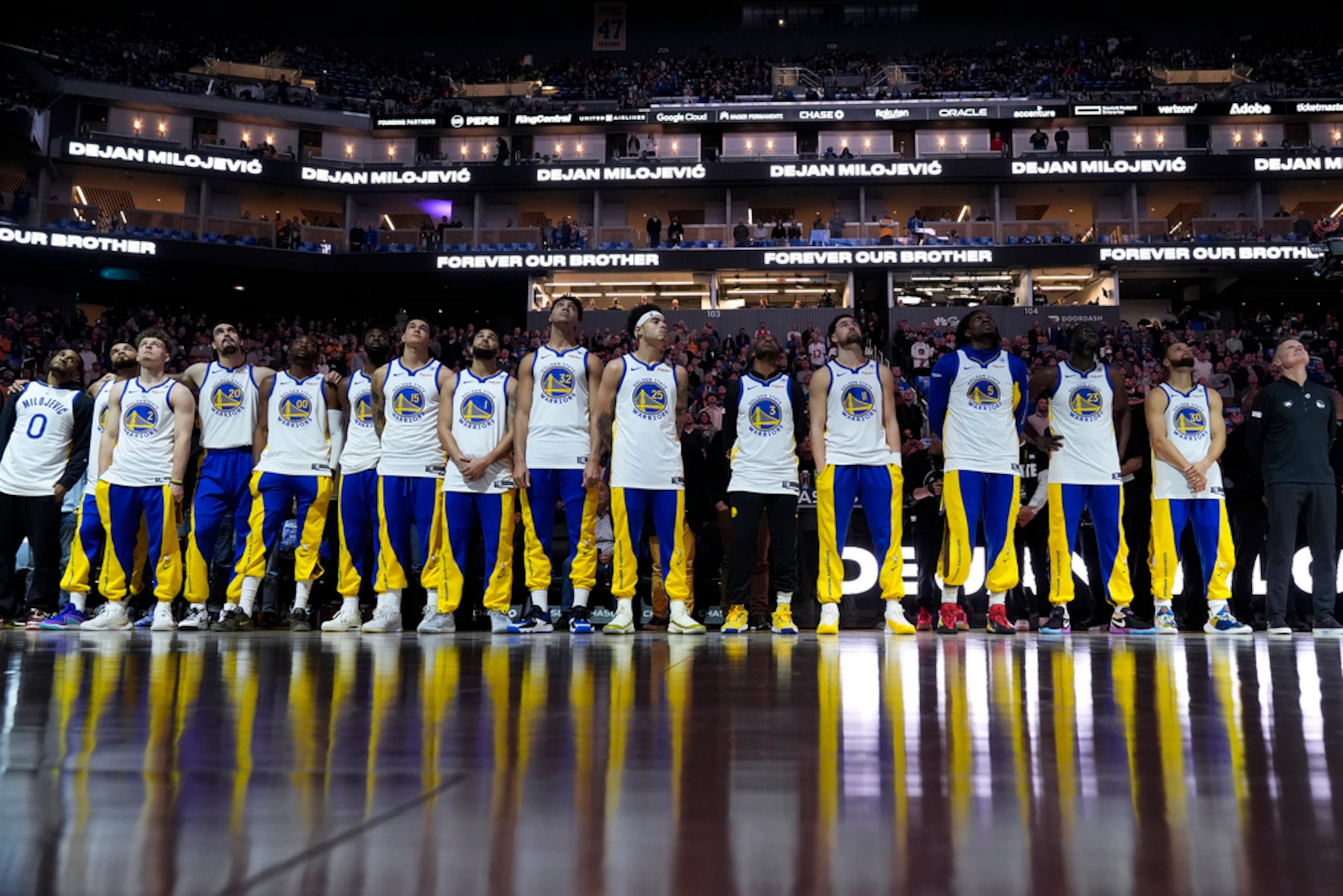 Los Warriors de Golden State observan un homenaje en video para Dejan Milojevic, el asistente recientemente fallecido.