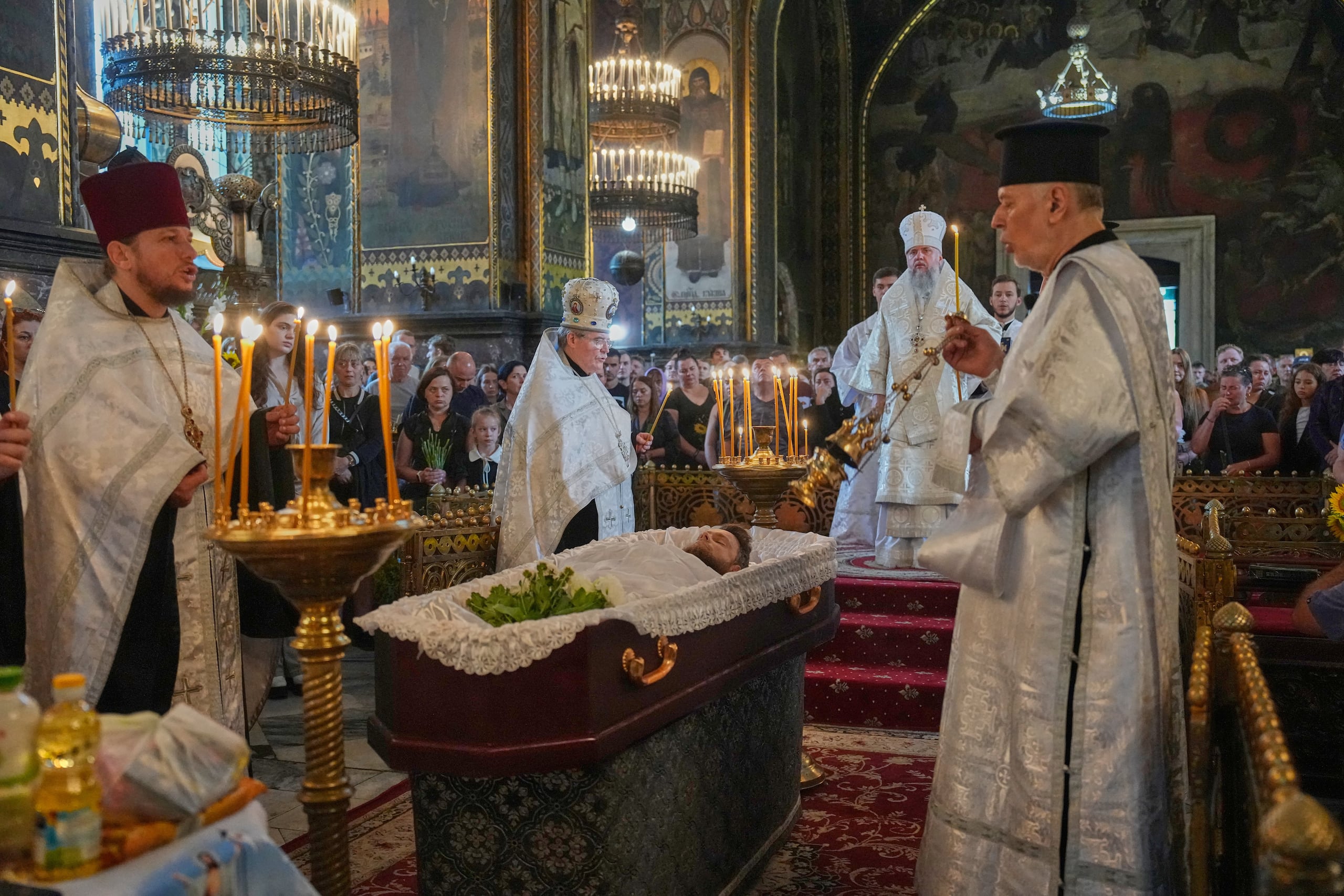 Sacerdotes presiden una ceremonia de despedida para Oleksiy Yukov, quien resultó herido de muerte mientras exhumaba los cuerpos de soldados caídos en el frente en la región de Donetsk, en la Catedral de San Volodymyr en Kiev, Ucrania, el sábado, 8 de agosto. (Foto AP/Efrem Lukatsky)