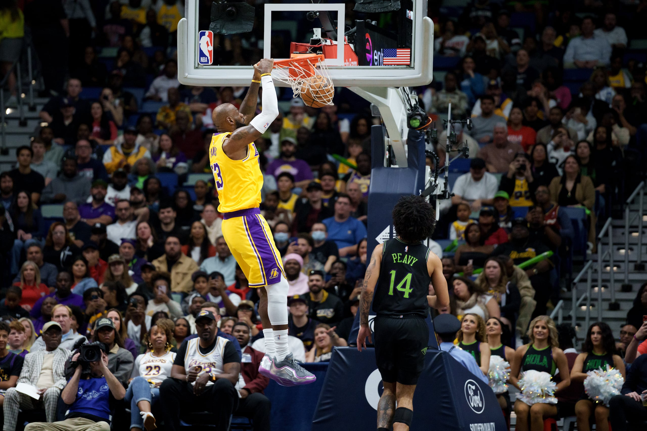 LeBron James (23), alero de los Lakers de Los Ángeles, realiza un mate junto al base Micah Peavy (14), de los Pelicans de Nueva Orleans, durante la primera mitad de un partido de baloncesto de la NBA en Nueva Orleans, hoy martes 6 de enero de 2026. (AP Photo/Matthew Hinton)