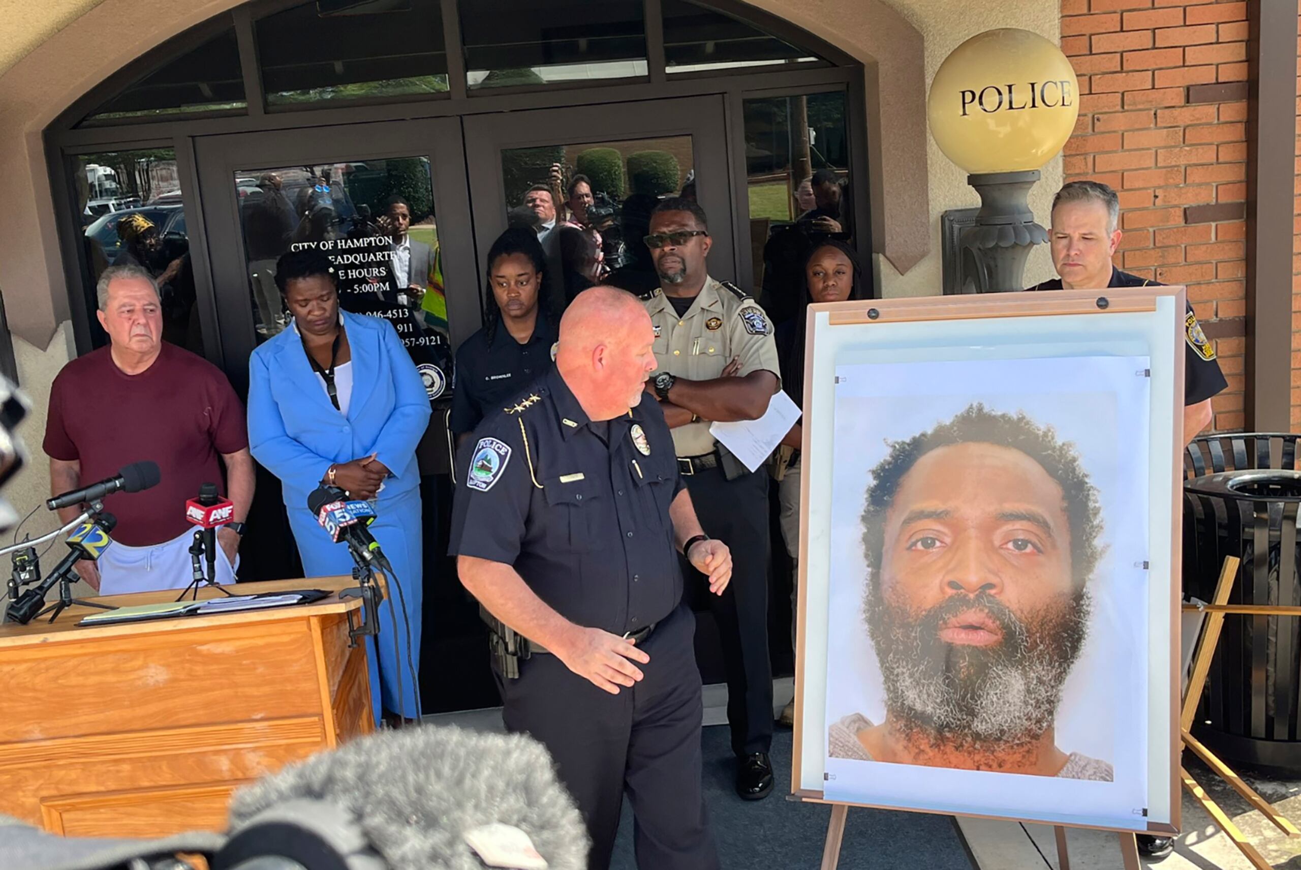 En esta imagen tuiteada por Steve Gehlbach, del canal de televisión WSB-TV, el jefe policial de la ciudad de Hampton, James Turner, al centro, muestra una fotografía de Andre Longmore durante una conferencia de prensa el sábado 15 de julio de 2023, en Hampton, Georgia. Longmore, sospechoso de cometer 4 homicidios, fue baleado de muerte por policías al día siguiente. (Steve Gehlbach/WSB-TV vía AP)