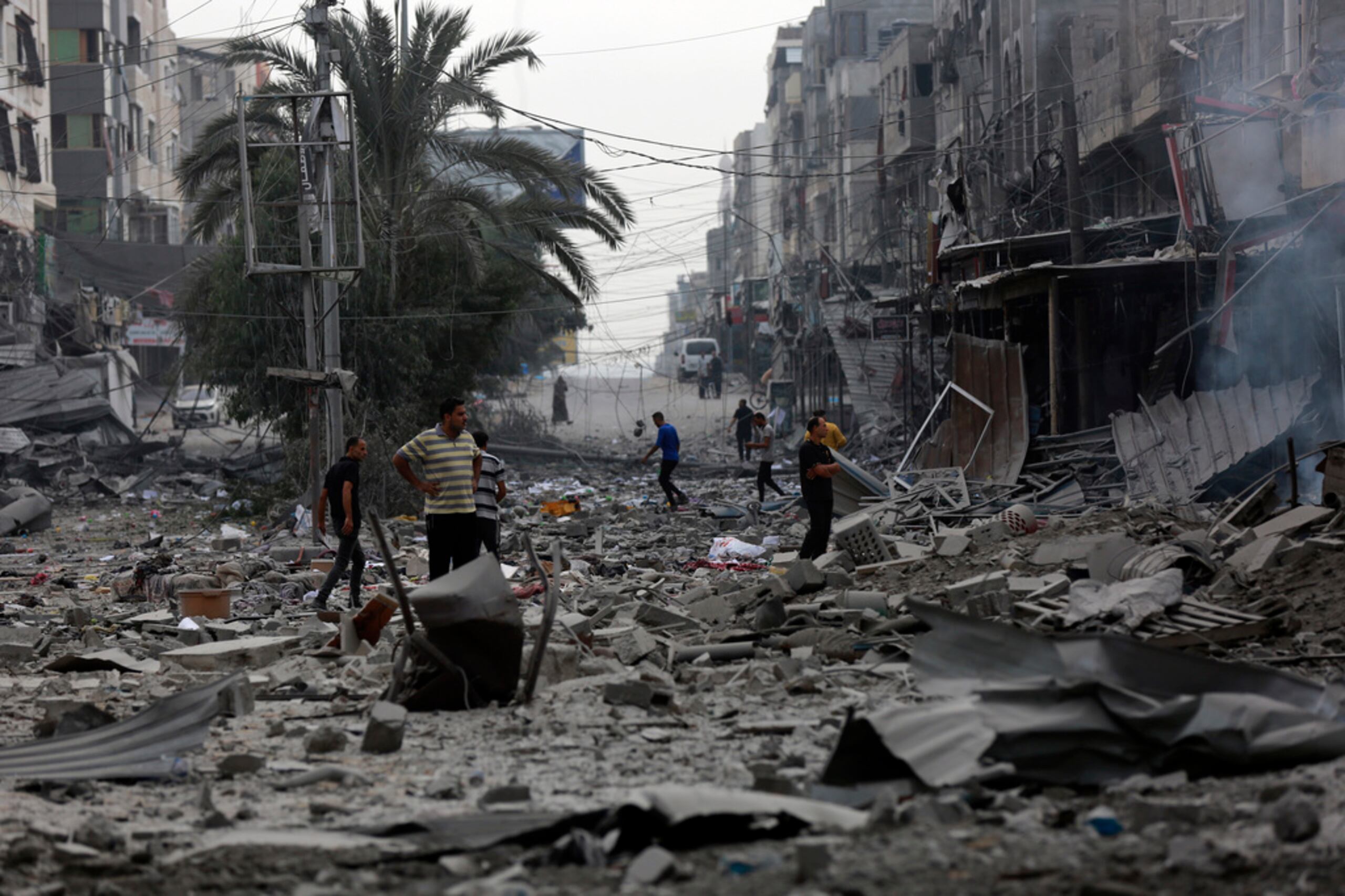 Palestinos inspeccionan los daños de los edificios destruidos tras ataques aéreos israelíes en la Ciudad de Gaza el 27 de octubre de 2023.