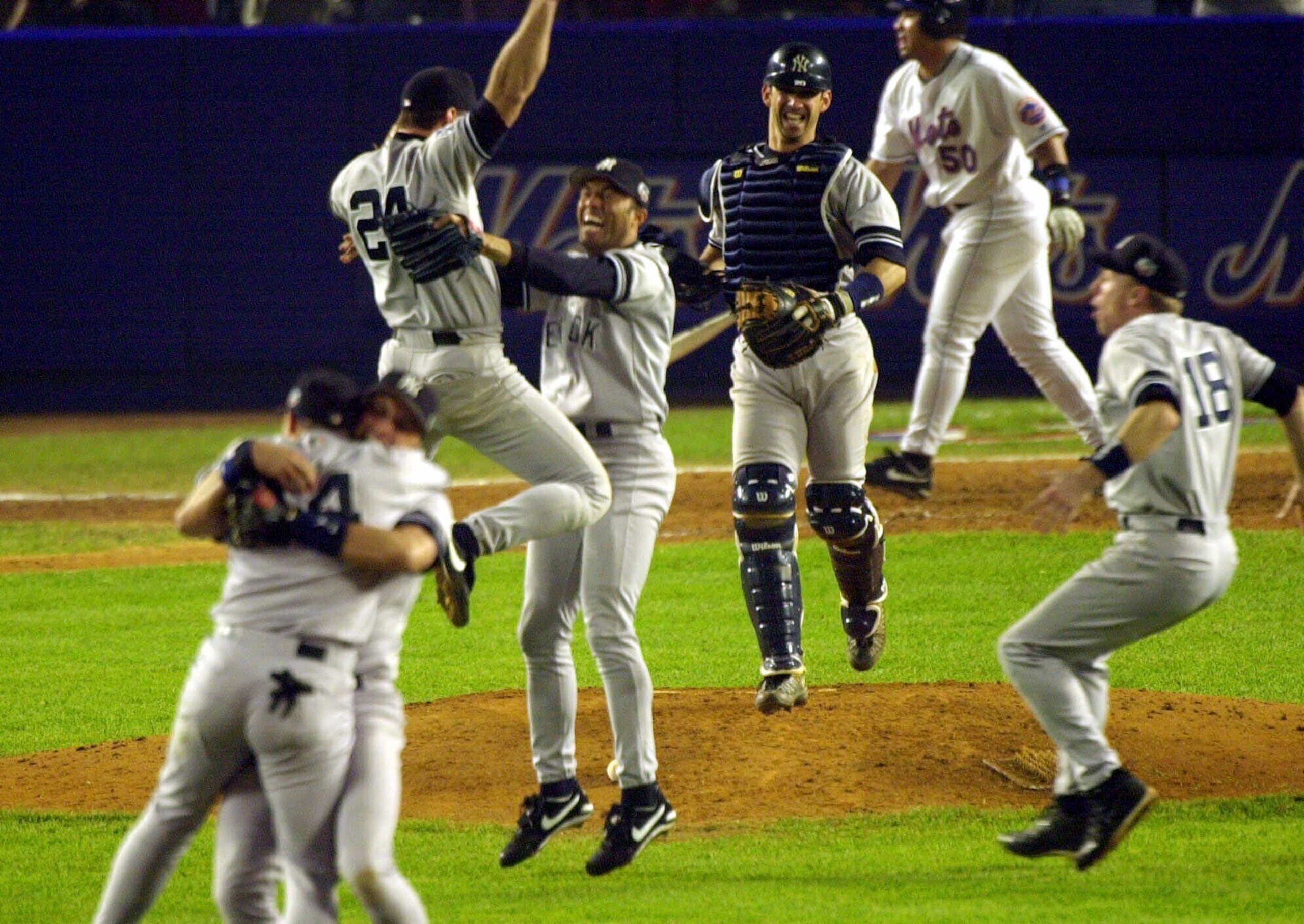 El primera base de los Yankees de Nueva York, Tino Martínez (24), salta a los brazos del lanzador Mariano Rivera mientras el receptor Jorge Posada, tercero desde la derecha, Scott Brosius (18) y otros celebran después de derrotar a los Mets de Nueva York en el Juego 5 de la Serie Mundial 4-2 para convertirse en los campeones de la Serie Mundial de 2000, el 26 de octubre de 2000, en el Shea Stadium de Nueva York.