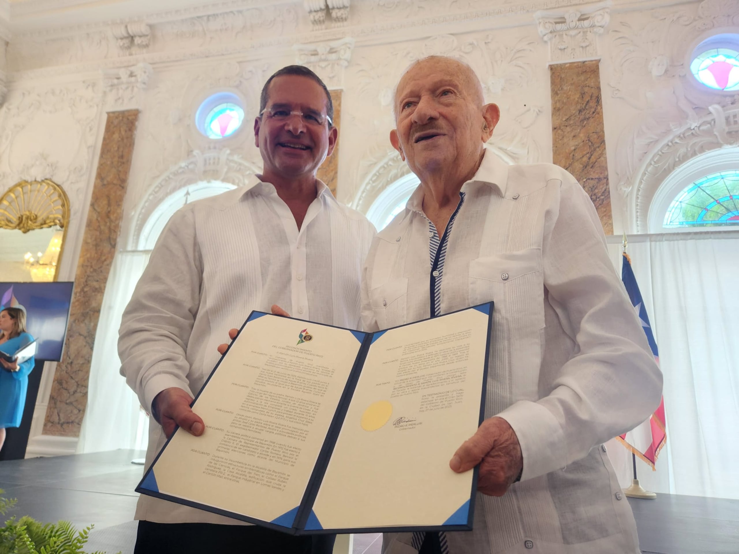 El gobernador Pedro Pierluisi le entrega una proclama de dedicatoria al exalcalde de Bayamón, Ramón Luis Rivera, padre, durante el acto de conmemoración del 166 natalicio de José Celso Barbosa.