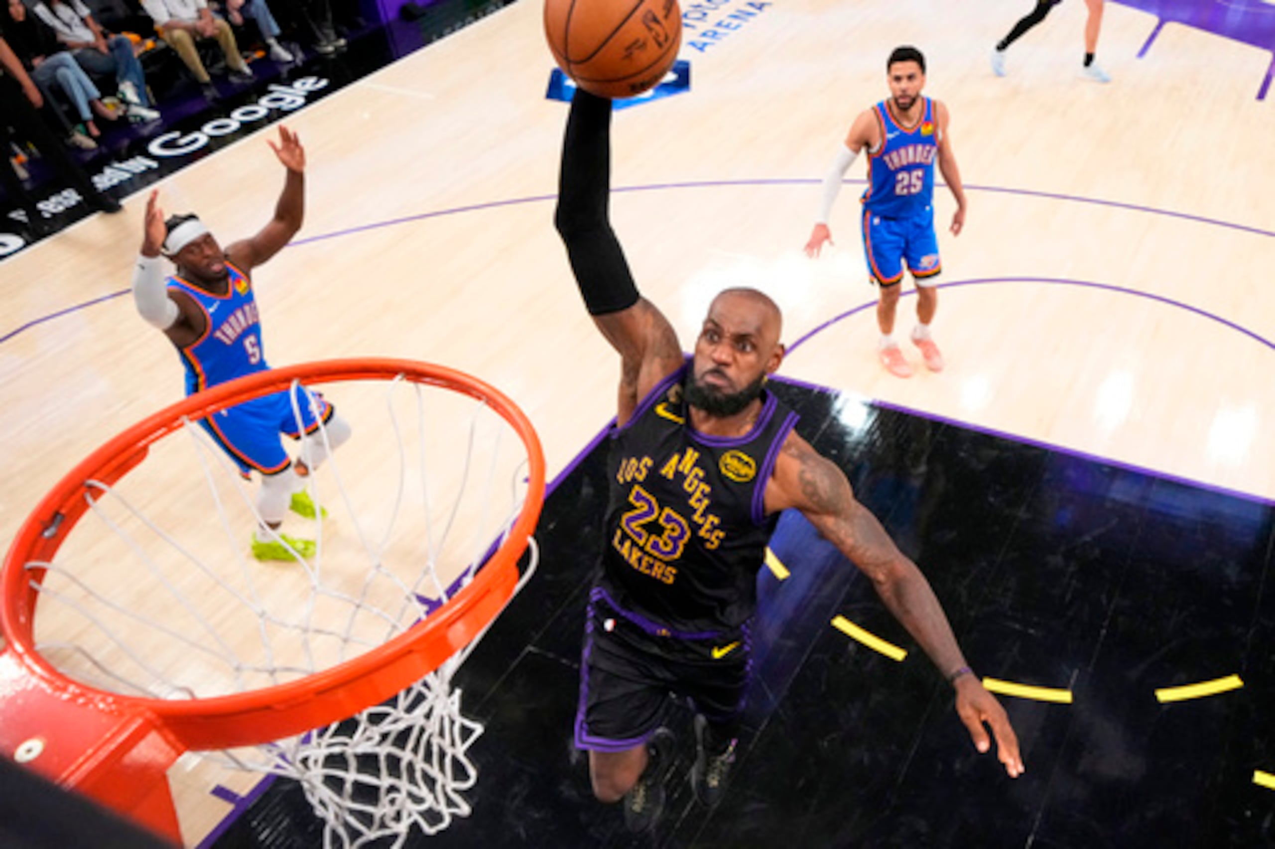 El alero de los Lakers de Los Ángeles LeBron James, en el centro, realiza un mate mientras el escolta de los Thunder de Oklahoma City Luguentz Dort, a la izquierda, y el escolta Ajay Mitchell observan durante la segunda mitad del cuarto partido de la segunda ronda de los playoffs de baloncesto de la NBA, el lunes 11 de mayo de 2026, en Los Ángeles. (AP Photo/Mark J. Terrill)