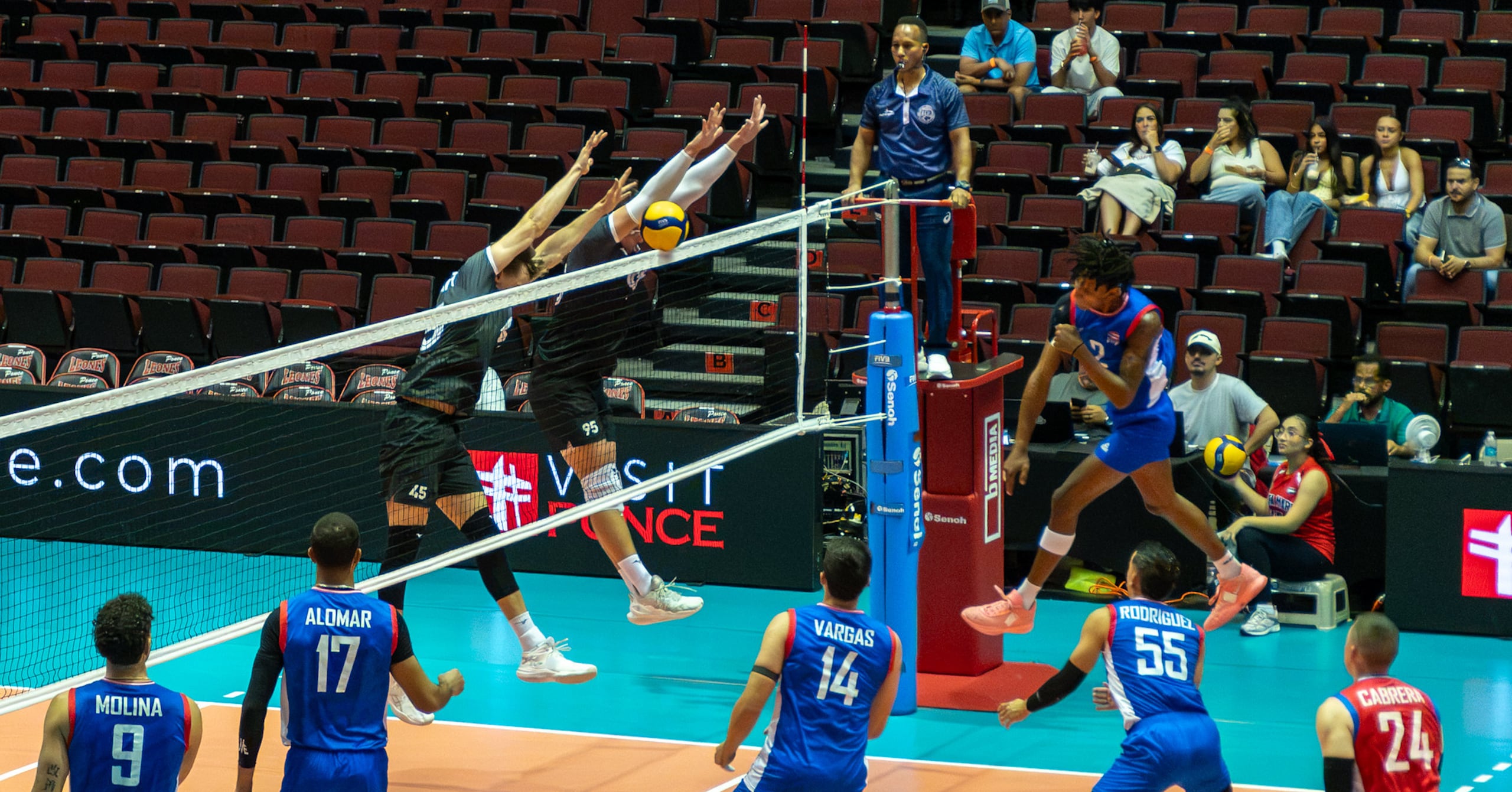 Klistan Lawrence le tira a la pelota ante el doble bloqueo de Canadá durante la acción del lunes del torneo Final Six de Norceca.