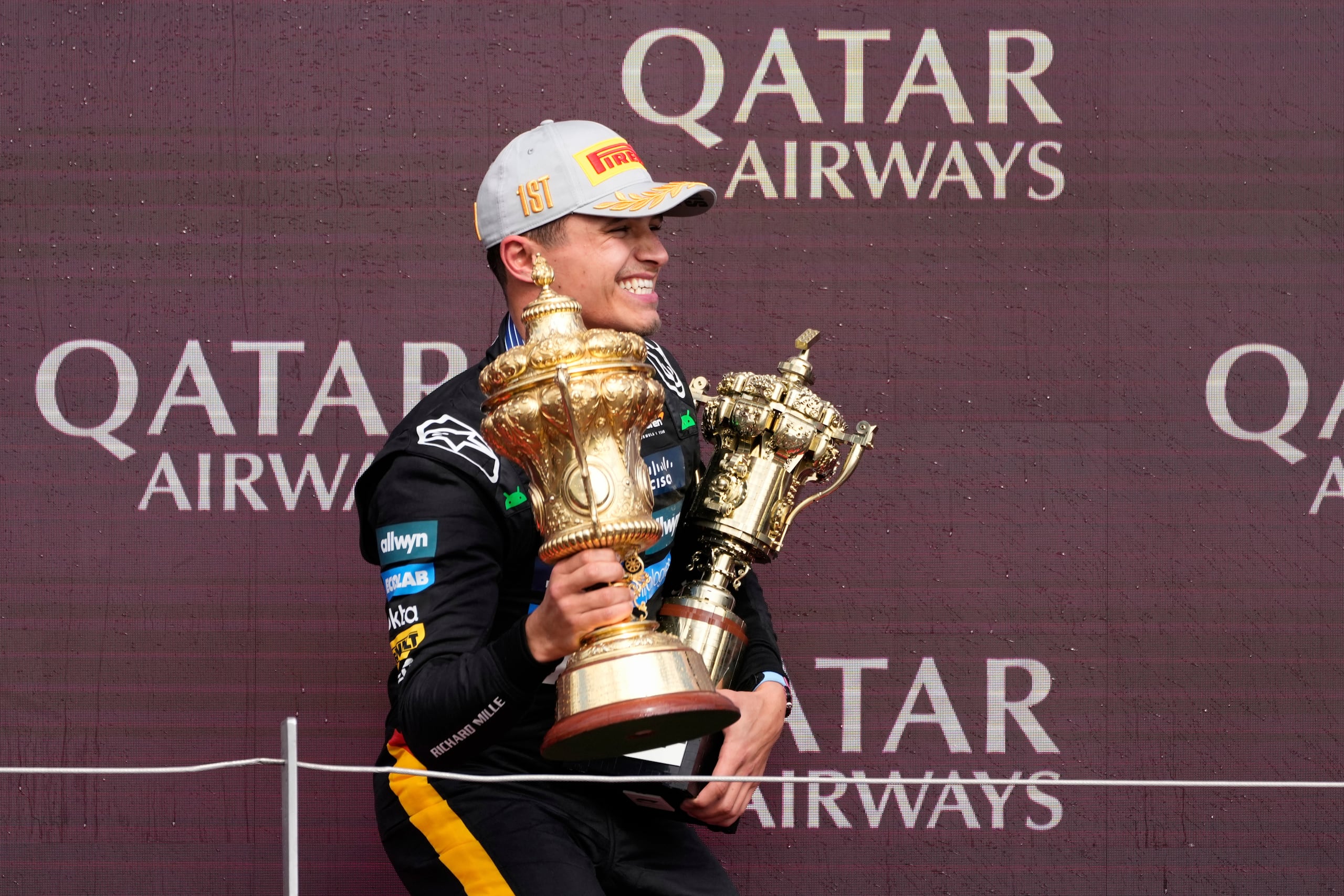 El británico Lando Norris de McLaren sostiene los trofeos en el podio para celebrar su triunfo en el Gran Premio de Gran Bretaña.