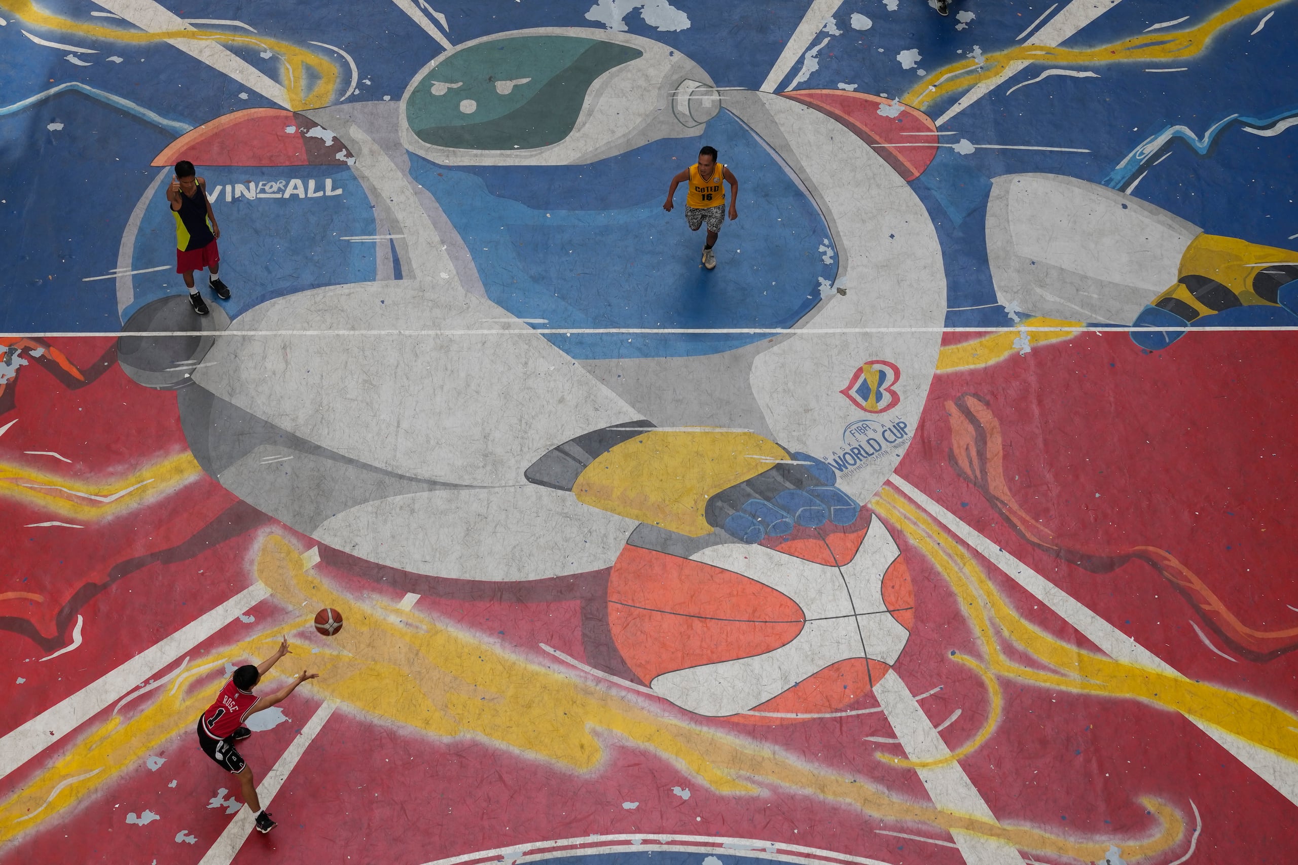 Otro grupo de jugadores aparecen aquí jugando baloncesto en una cancha aficionada de Filipinas.