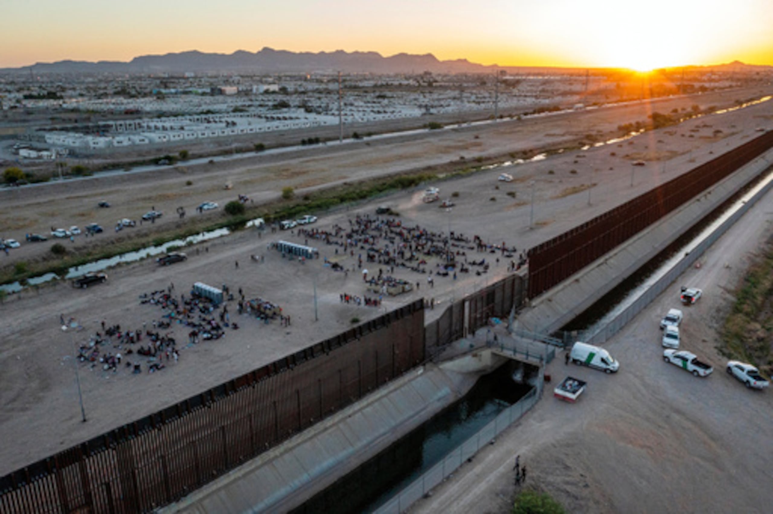 ARCHIVO - Mientras el sol se pone, los migrantes esperan fuera de una puerta en la valla fronteriza para entrar en El Paso, Texas, para ser procesados por la Patrulla Fronteriza, 11 de mayo de 2023. (AP Photo/Andres Leighton, Archivo)
