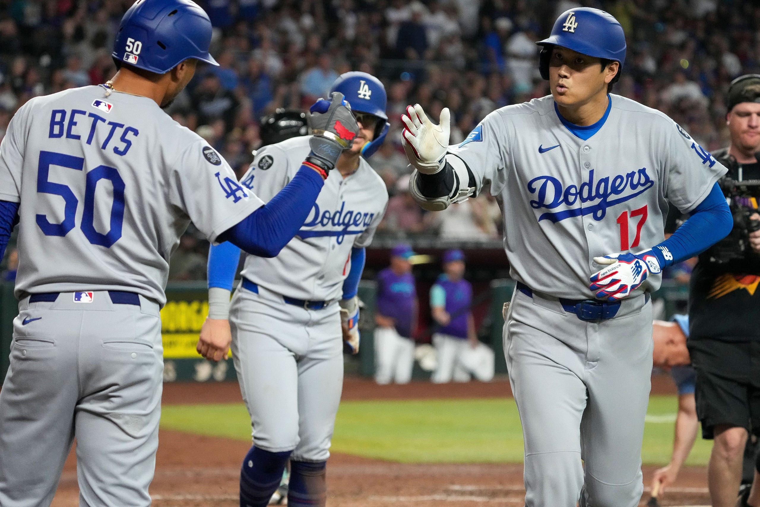 Shohei Ohtani saluda a Mookie Betts tras conectar un cuadrangular frente a los Diamondbacks de Arizona. En el fondo, el puertorriqueño Kike Hernández.