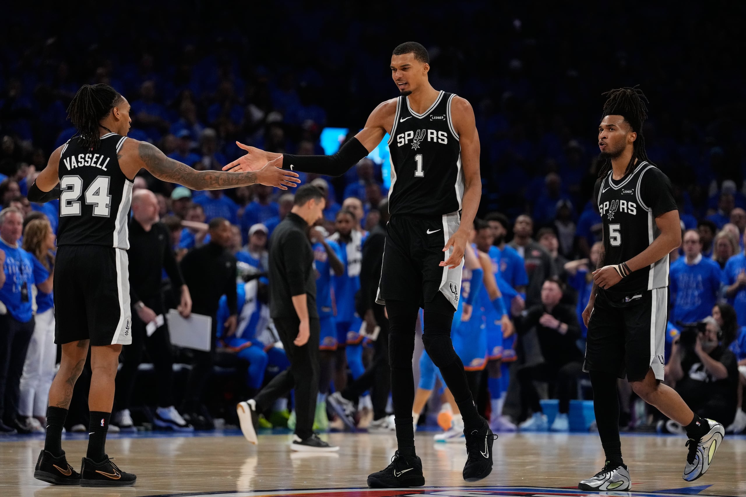 El alero de los Spurs de San Antonio Victor Wembanyama celebra con sus compañeros Devin Vassell (24) y Stephon Castle en el juego 1 de las Finales de la Conferencia Oeste ante el Thunder de Oklahoma City el lunes 18 de mayo del 2026. (AP Foto/Tony Gutierrez)