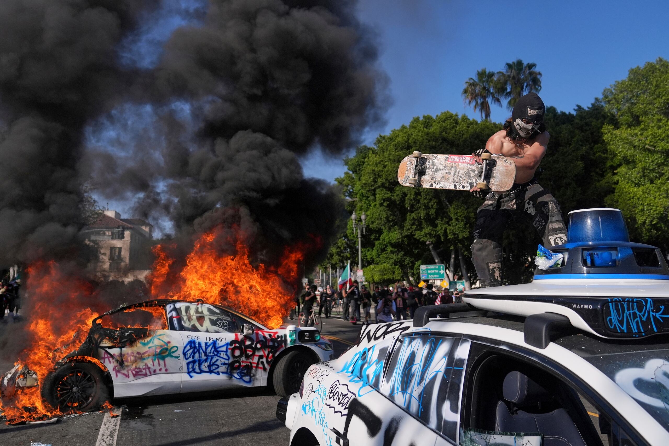 Un Waymo es vandalizado mientras otro se quema cerca del centro de detención metropolitano del centro de Los Ángeles, el domingo 8 de junio de 2025, luego de la protesta por la redada de inmigración de anoche.