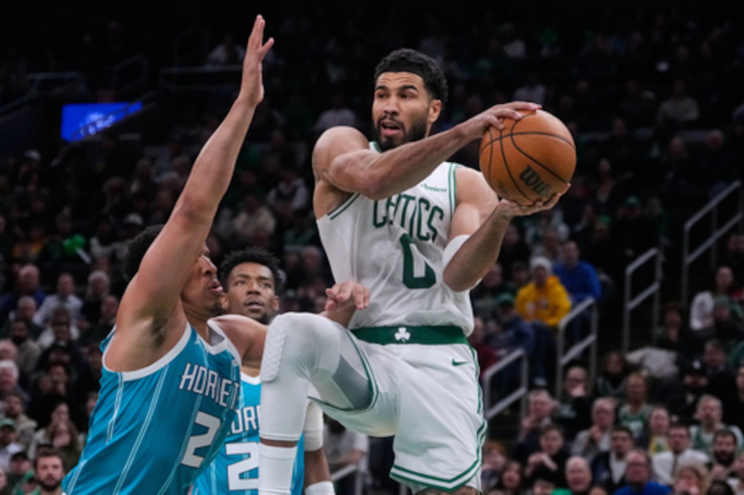 El alero de los Boston Celtics Jayson Tatum (0) busca un pase mientras es cubierto por el alero de los Charlotte Hornets Grant Williams (2) durante la segunda mitad de un partido de baloncesto de la NBA, el martes 7 de abril de 2026, en Boston. (AP Photo/Charles Krupa)