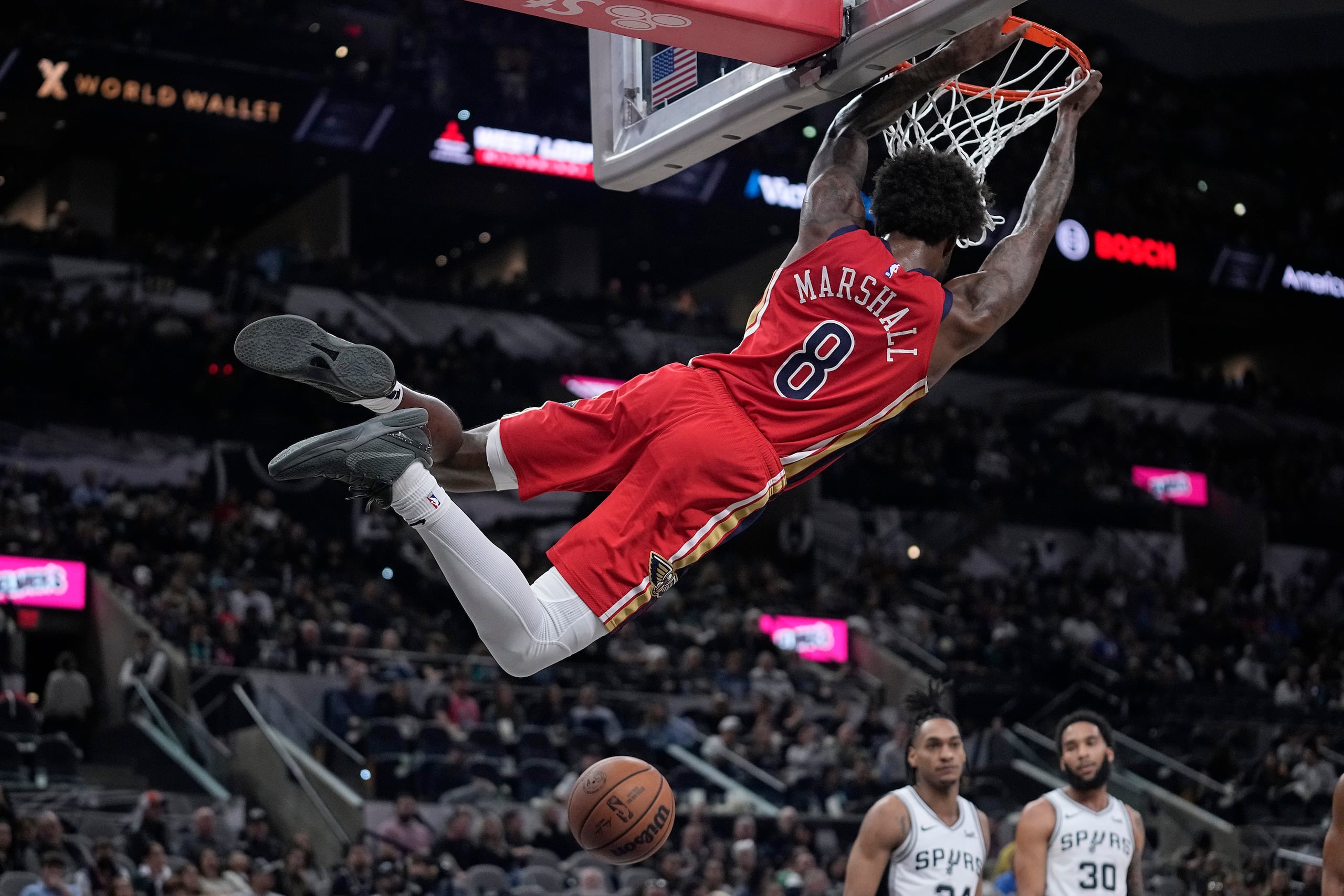 Naji Marshall (8), de los Pelicans de Nueva Orleans, se balancea en el aro después de una clavada en contra de los Spurs de San Antonio, durante la segunda mitad del juego de baloncesto de la NBA, en San Antonio.