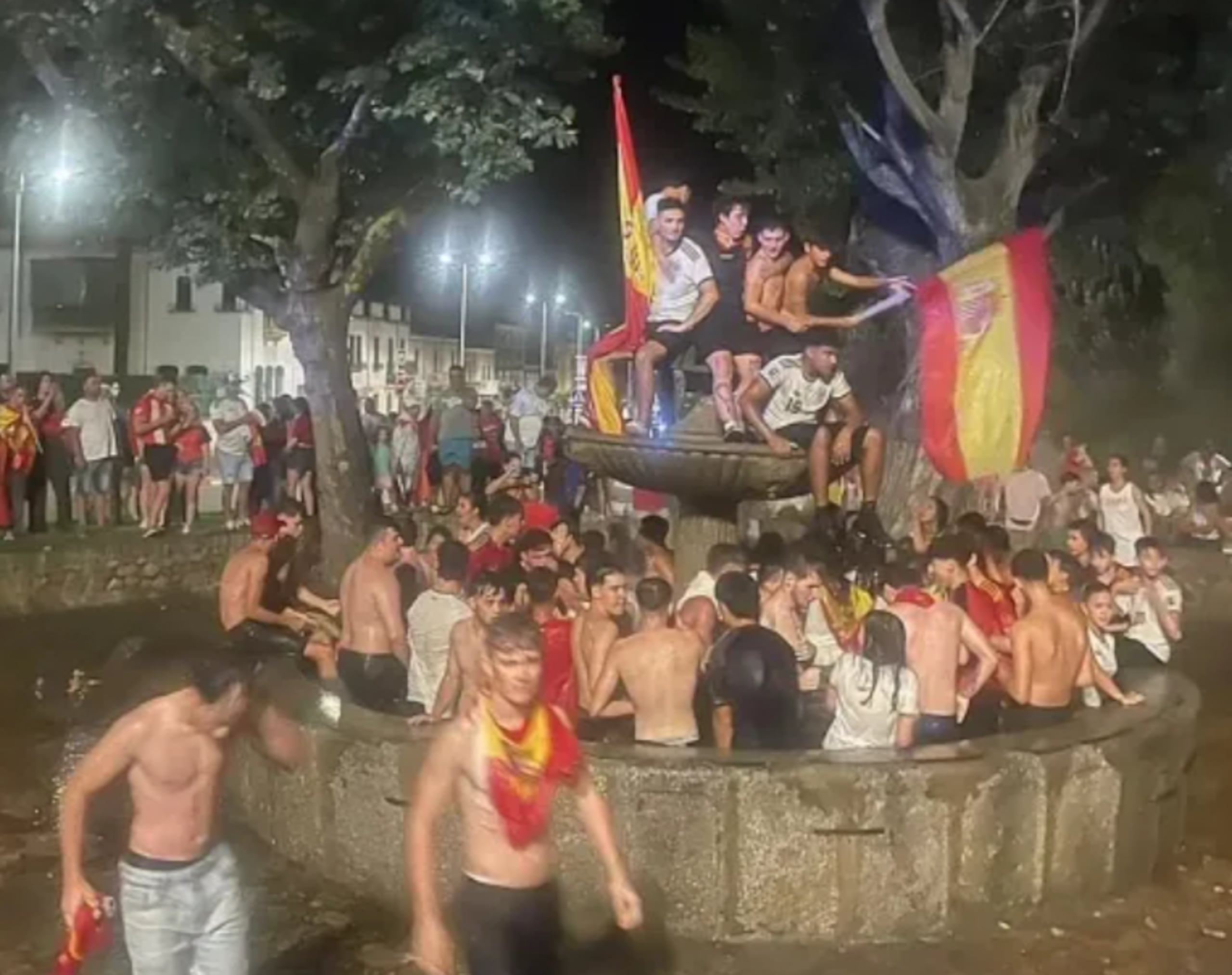 Personas aglomeradas en fuente celebrando la victoria de España en el Mundial de la FIFA