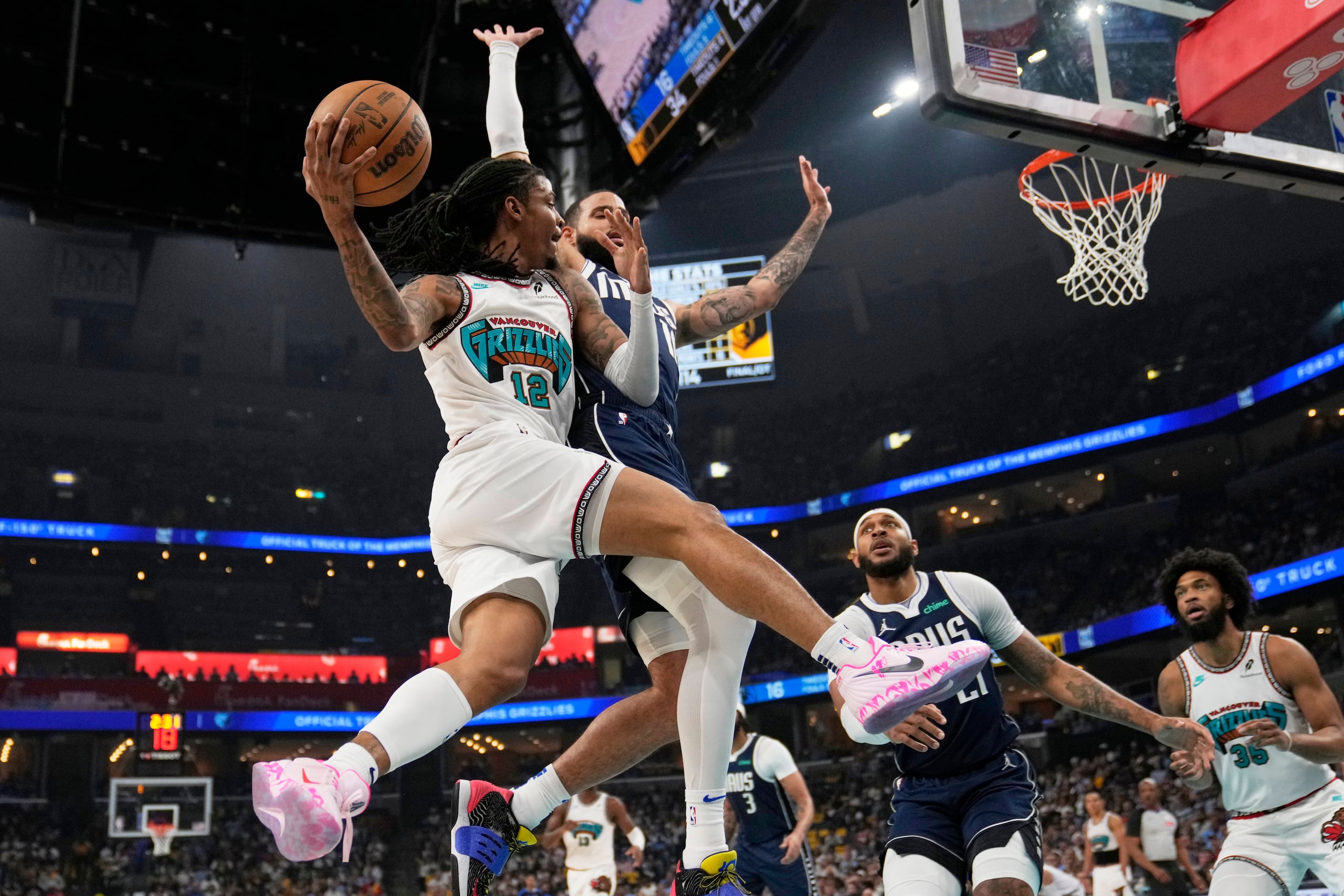 Ja Morant, de los Grizzlies de Memphis, pasa el balón ante la marca defensiva de Caleb Martin, de los Mavericks de Dallas.