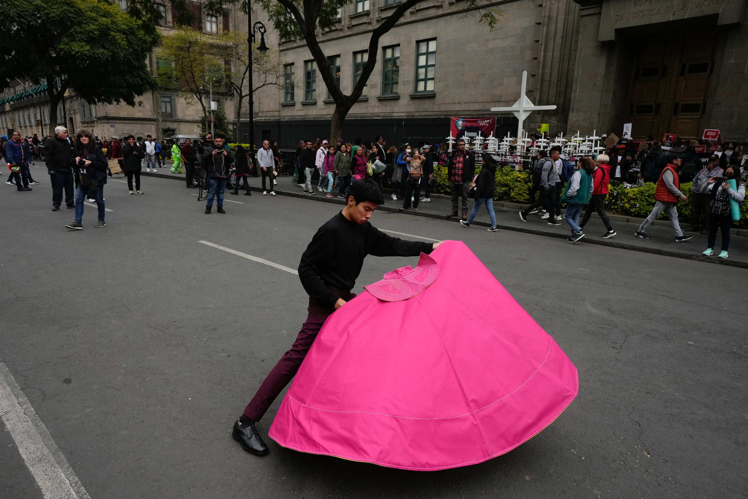 Juan Pablo Vargas hace movimientos del toreo con un capote en una protesta en la que defensores y críticos de las corridas de todos se reunieron a las afueras de la Suprema Corte, en Ciudad de México, el miércoles 6 de diciembre de 2023. La Suprema Corte de México tenía previsto decidir si reactivaba las corridas en la capital, un año después de que fueran prohibidas. (AP Foto/Fernando Llano)