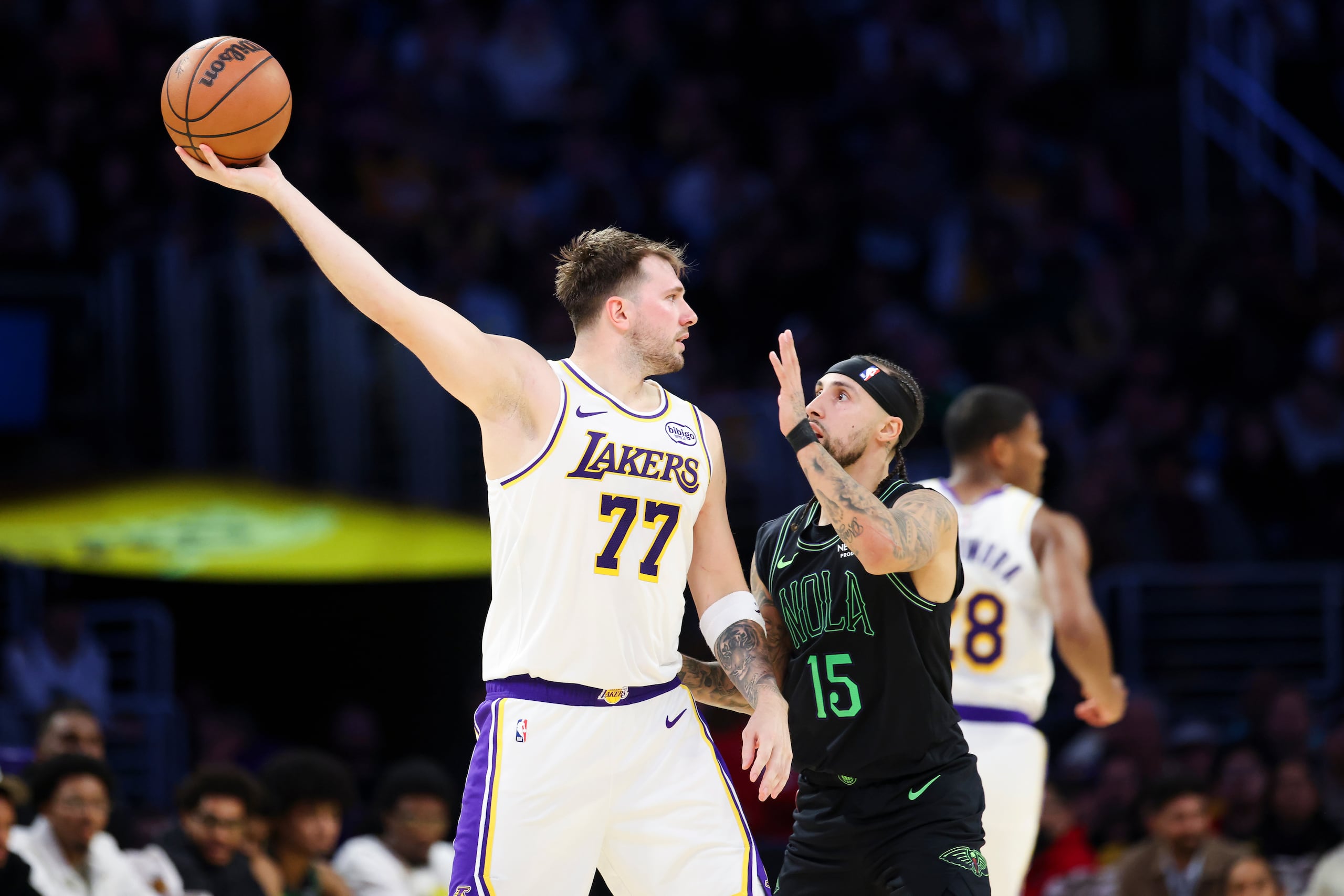 Luka Doncic (77), de los Lakers de Los Ángeles, sostiene el balón lejos de Jose Alvarado (15), de los Pelicans de Nueva Orleans, durante la primera mitad del juego de baloncesto de la NBA, el domingo 30 de noviembre de 2025, en Los Ángeles. (AP Foto/Jessie Alcheh)
