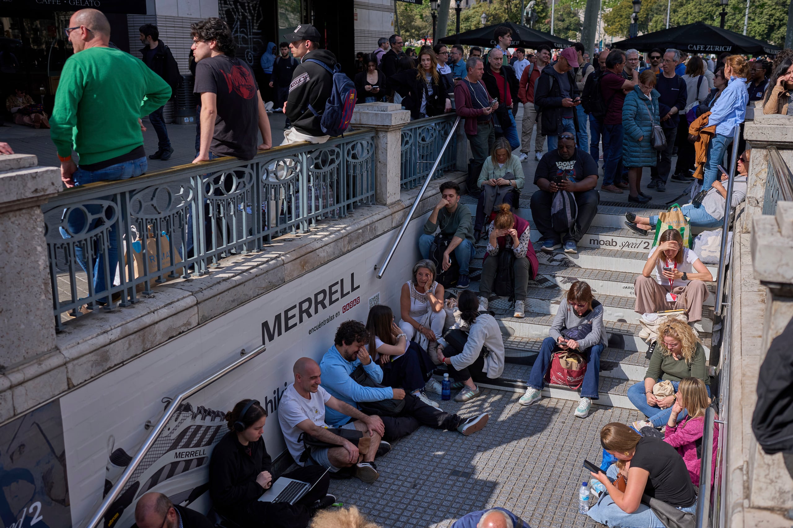 La gente espera fuera de una estación de metro cerrada, durante un apagón en Barcelona, España.