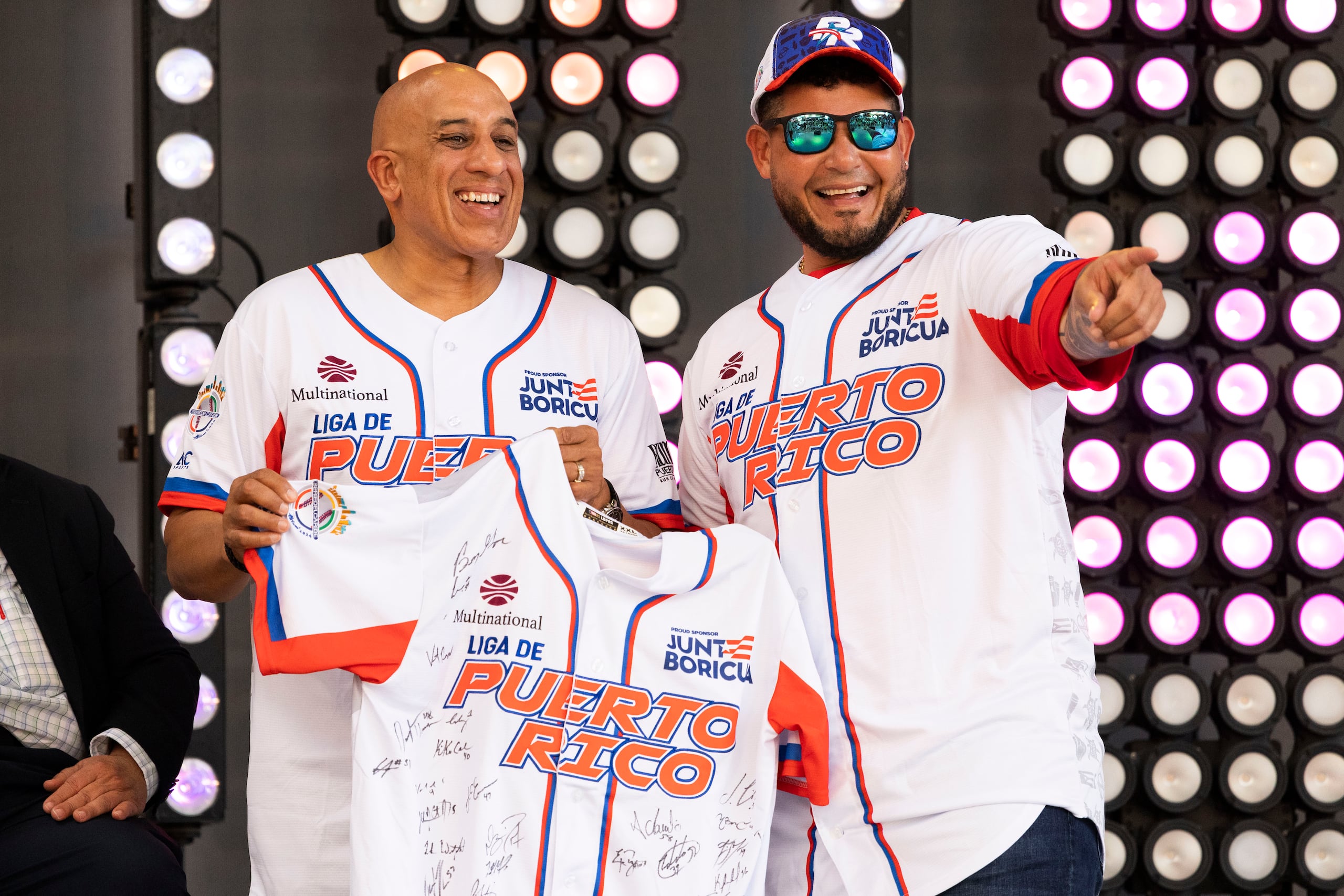 El gerente general de los Criollos de Puerto Rico, Carlos Berroa, y su dirigente Yadier Molina la pasan bien al mostrar la camiseta que vestirá la novena de Puerto Rico autografiada por todos sus integrantes en una actividad celebrada este lunes en el Distrito de Convenciones.