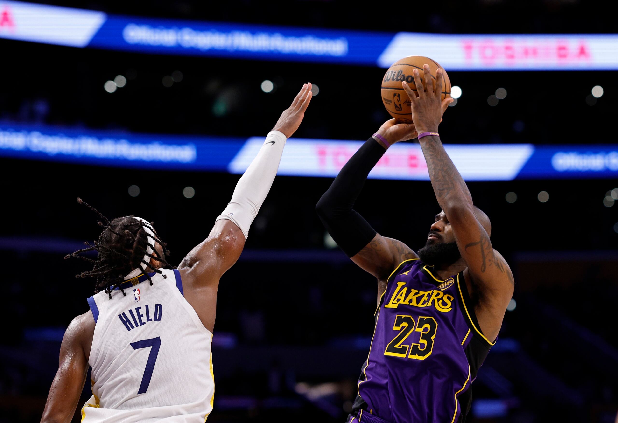 LeBron James, alero de los Lakers de Los Ángeles, lanza el balón a distancia frente al base de los Warriors de Golden State Buddy Hield.