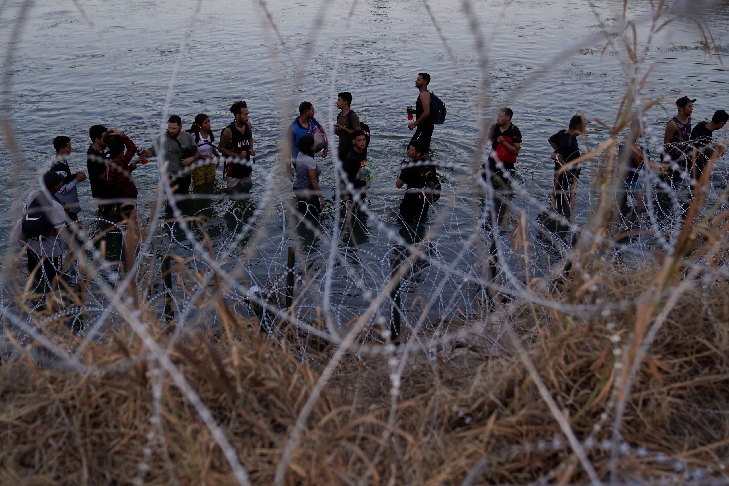 Imagen de migrantes que esperan para trepar por encima del alambre de púas después de cruzar el Río Bravo y entrar en Estados Unidos desde México.