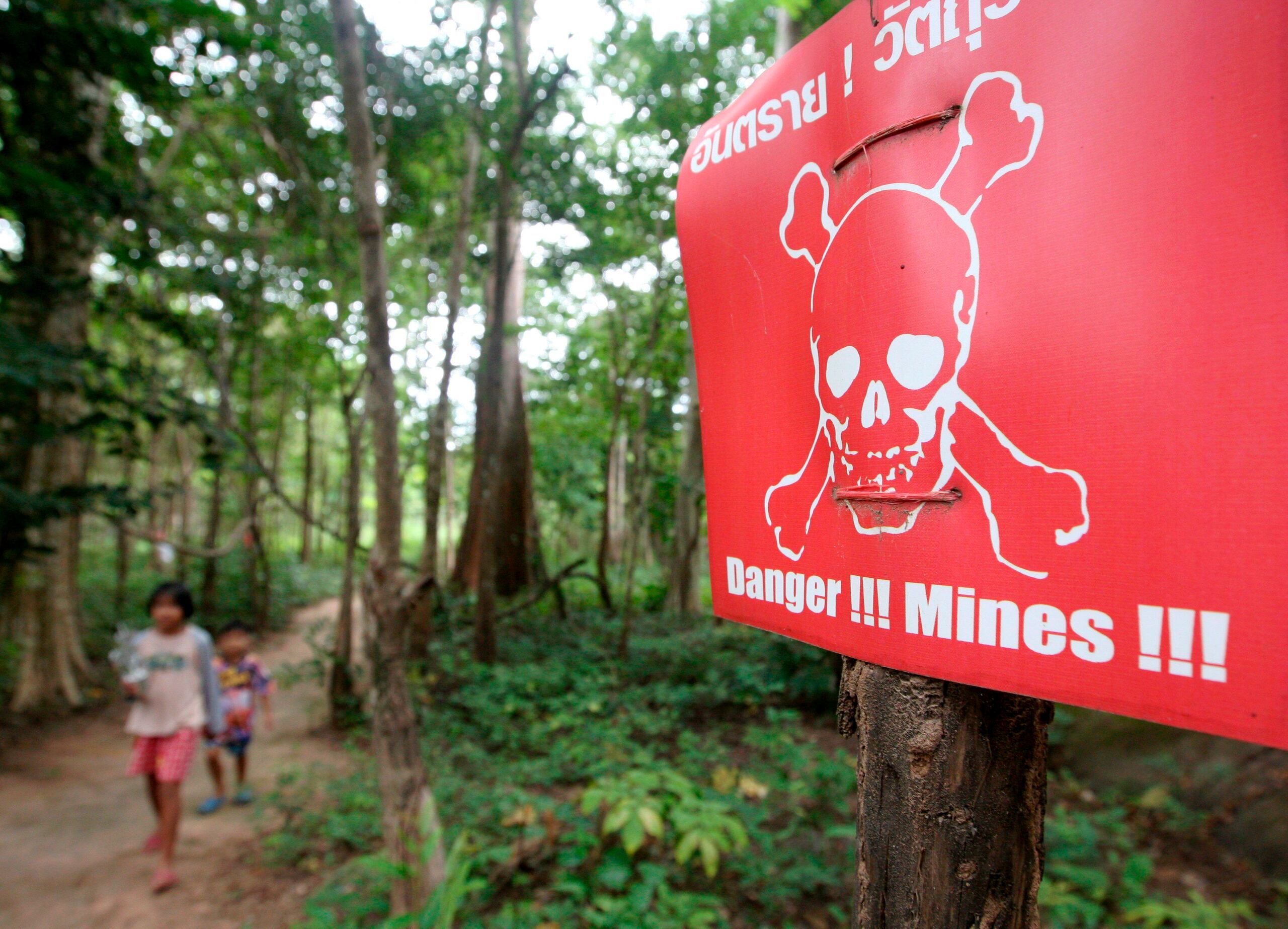 Foto de archivo de varios niños pasando cerca de una señal que advierte de la existencia de un campo de minas en una zona de conflicto entre Tailandia y Camboya. EFE/Rungroj Yongrit