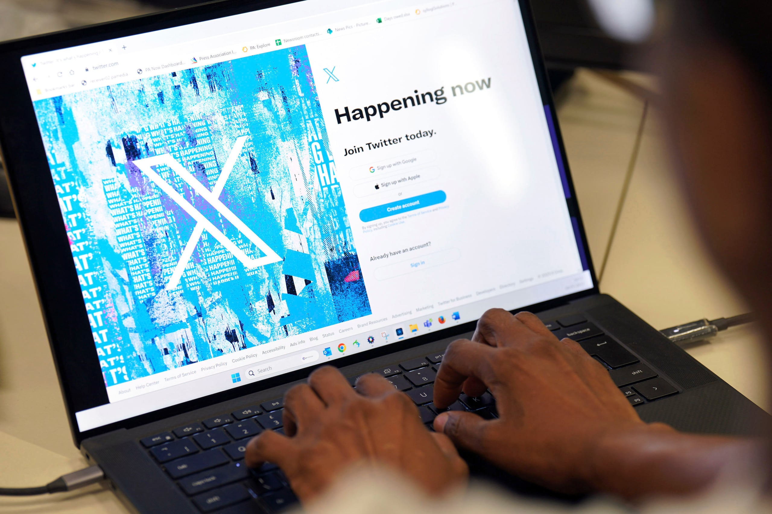 Una persona posa para una foto mientras se registra en Twitter, en una pantalla que muestra el nuevo logotipo de la plataforma, en una oficina en el centro de Londres, el lunes 24 de julio de 2023. (Jonathan Brady/PA via AP)