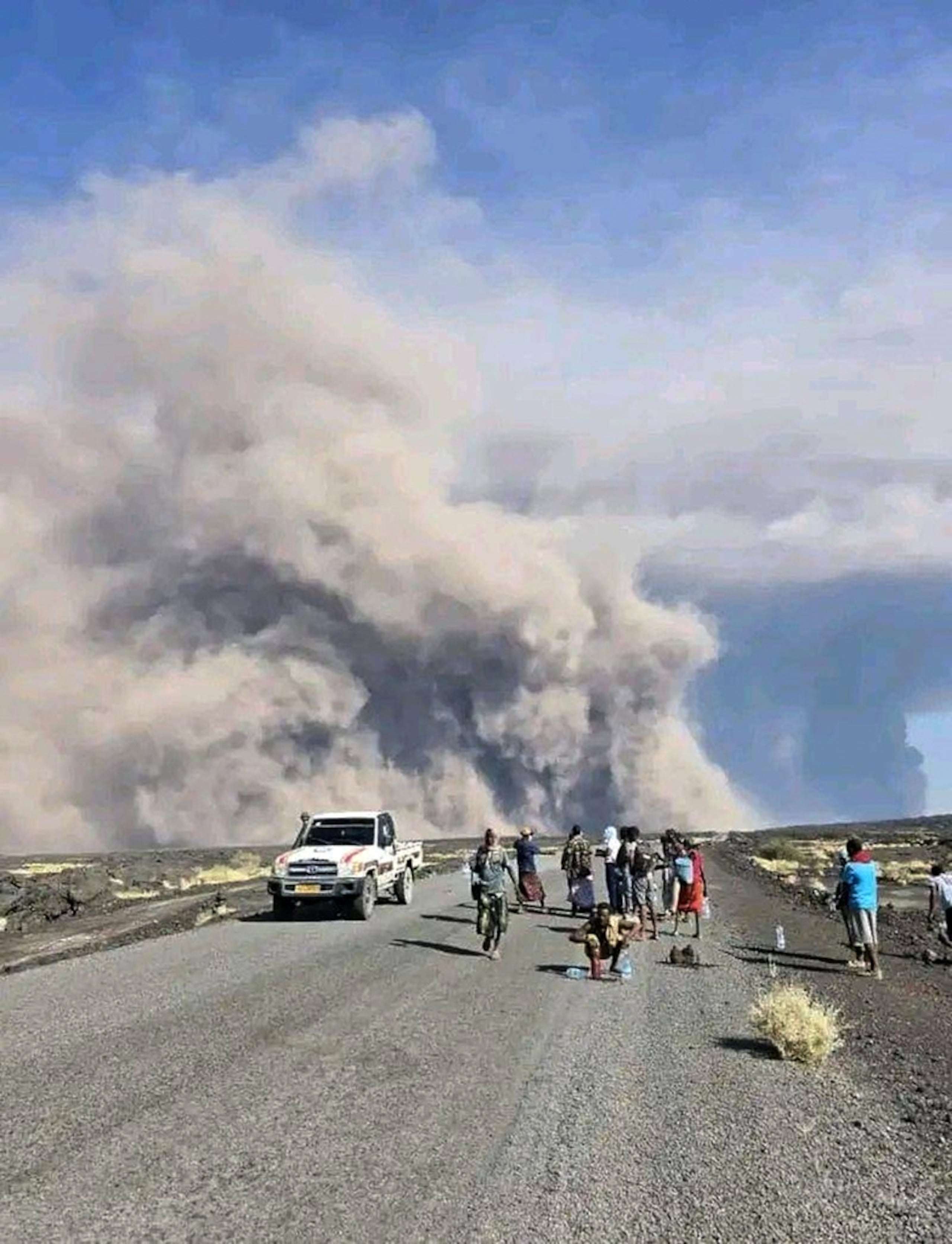 En esta foto publicada por la Oficina de Comunicación del Gobierno de Afar, un grupo de personas observa la columna de cenizas de una erupción del volcán Hayli Gubbi en la región de Afar, Etiopía, el 23 de noviembre.