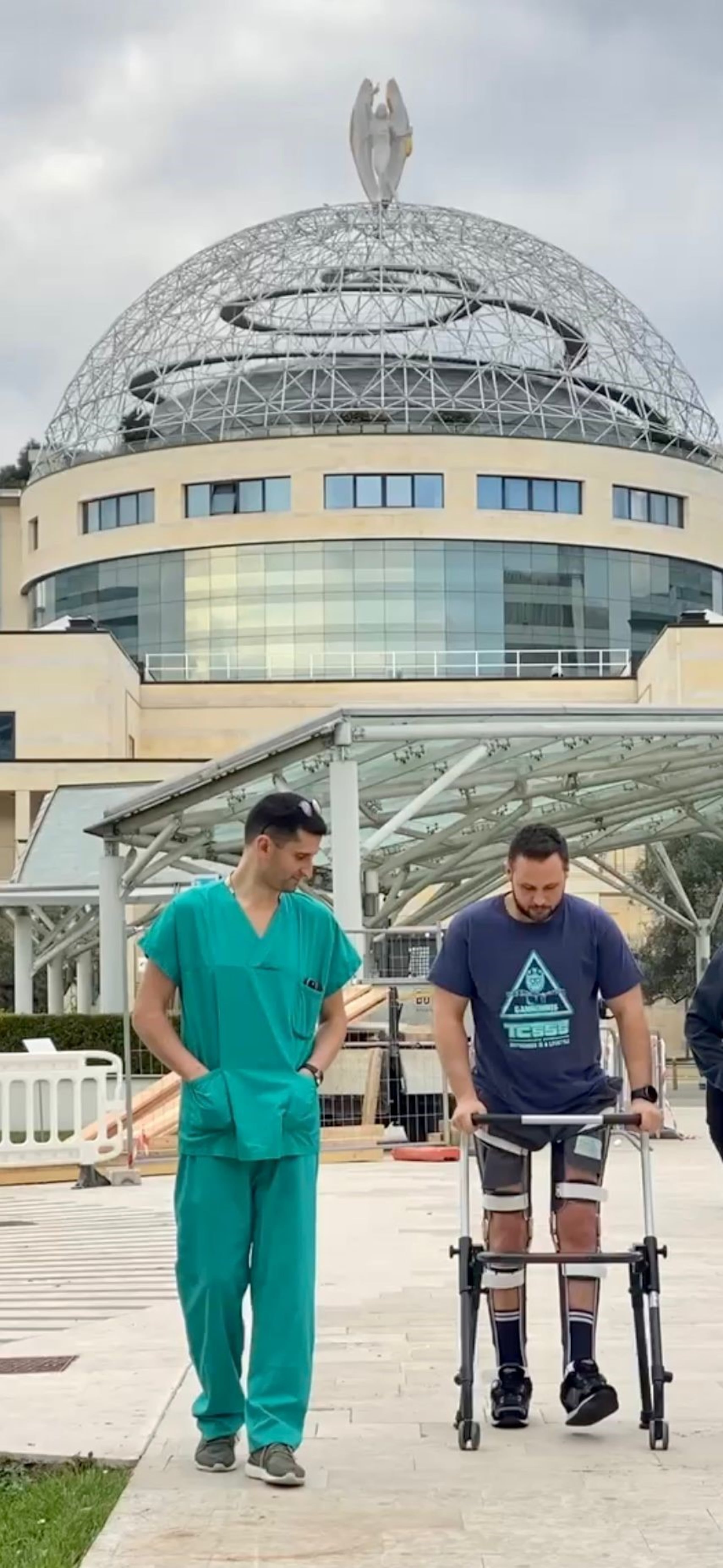 El paciente camina a la puerta del hospital junto al doctor Luigi Albano.