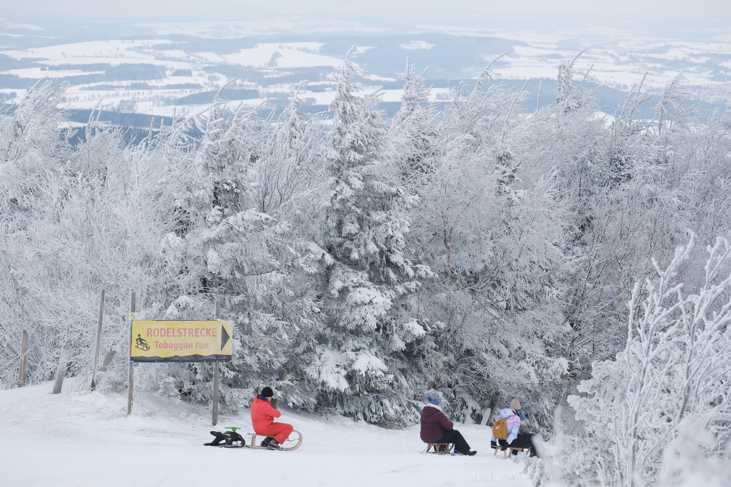 Personas en trineos en la cima del Fichtelberg, Oberwiesentha, Alemania, sábado 4 de enero de 2025. (Sebastian Willnow/dpa via AP)