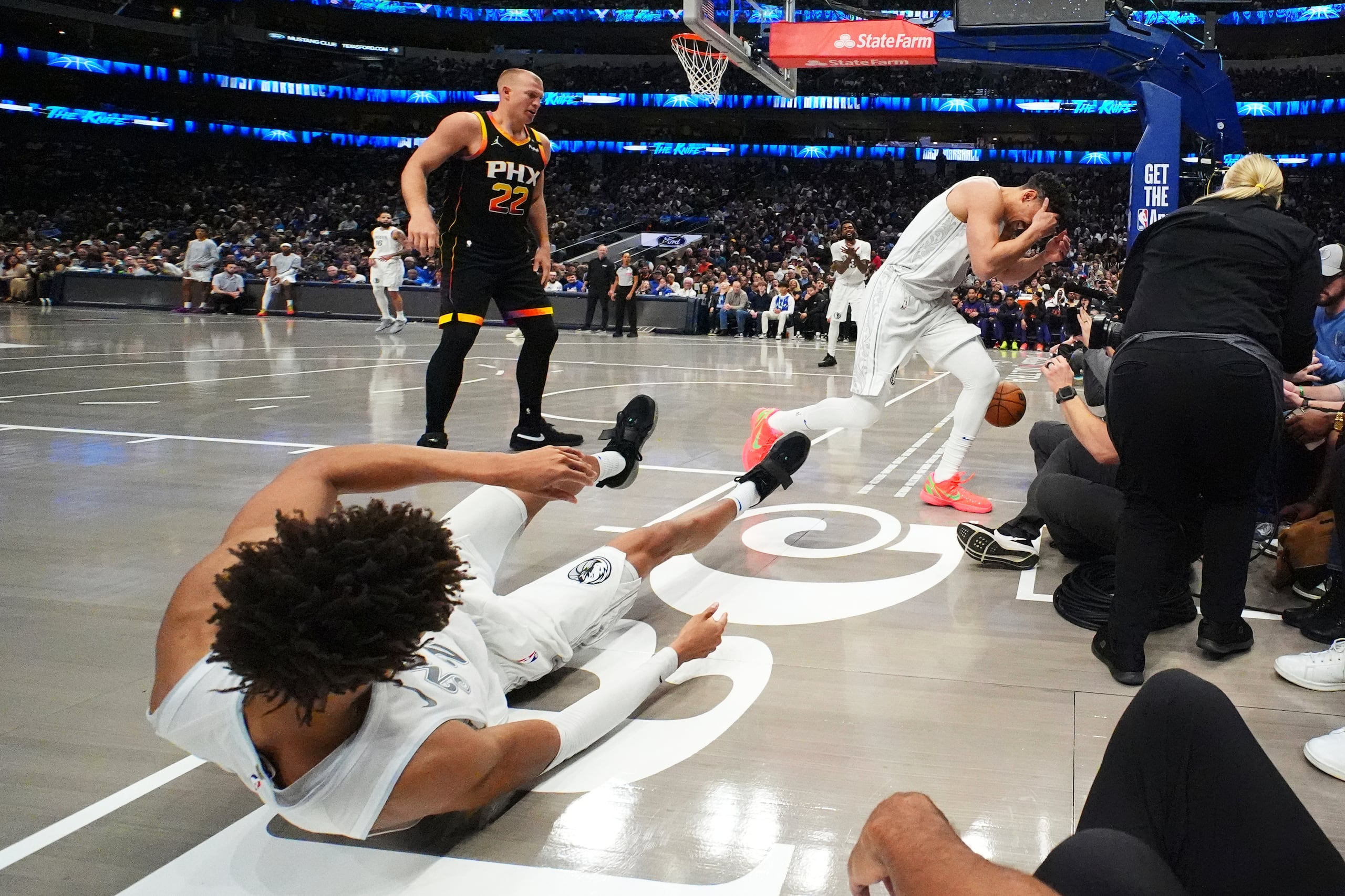 Kessler Edwards, izquierda, y Dwight Powell, de los Mavericks de Dallas, reaccionan después de chocar y golpearse las cabezas mientras buscaban un rebote en un partido de baloncesto de la NBA frente a los Suns de Phoenix.