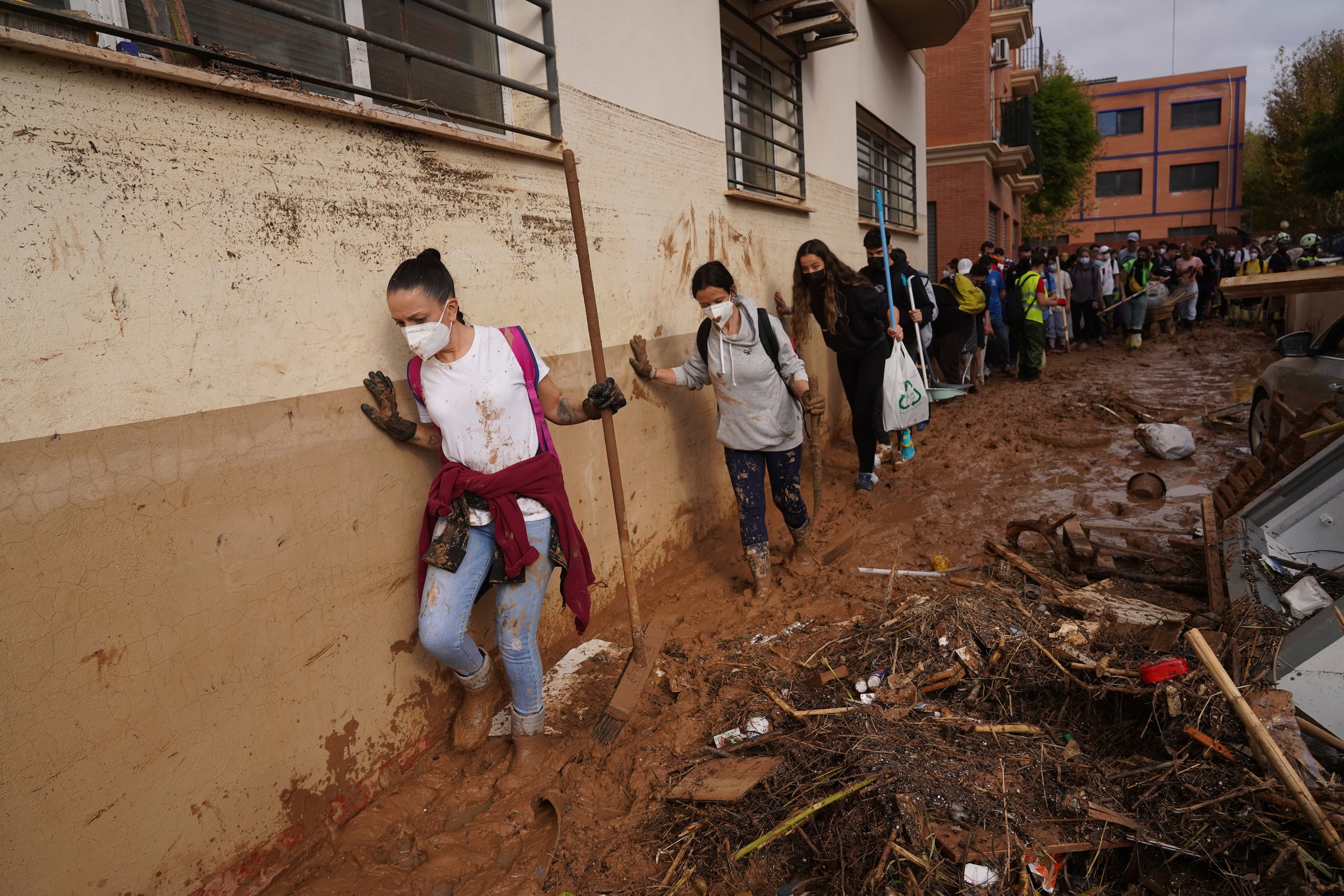 Voluntarios caminan entre el lodo para colaborar en las tareas de limpieza tras las inundaciones que arrasaron Massanassa, a las afueras de Valencia, España.